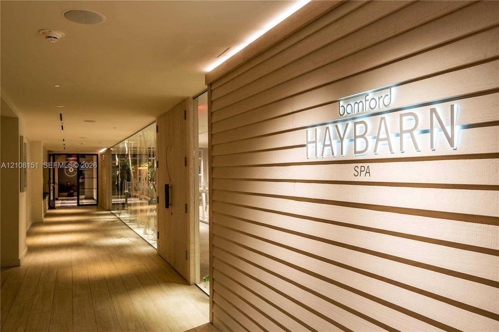 Hallway featuring horizontal wood paneling, recessed lighting, glass partition wall, and wood-finish flooring