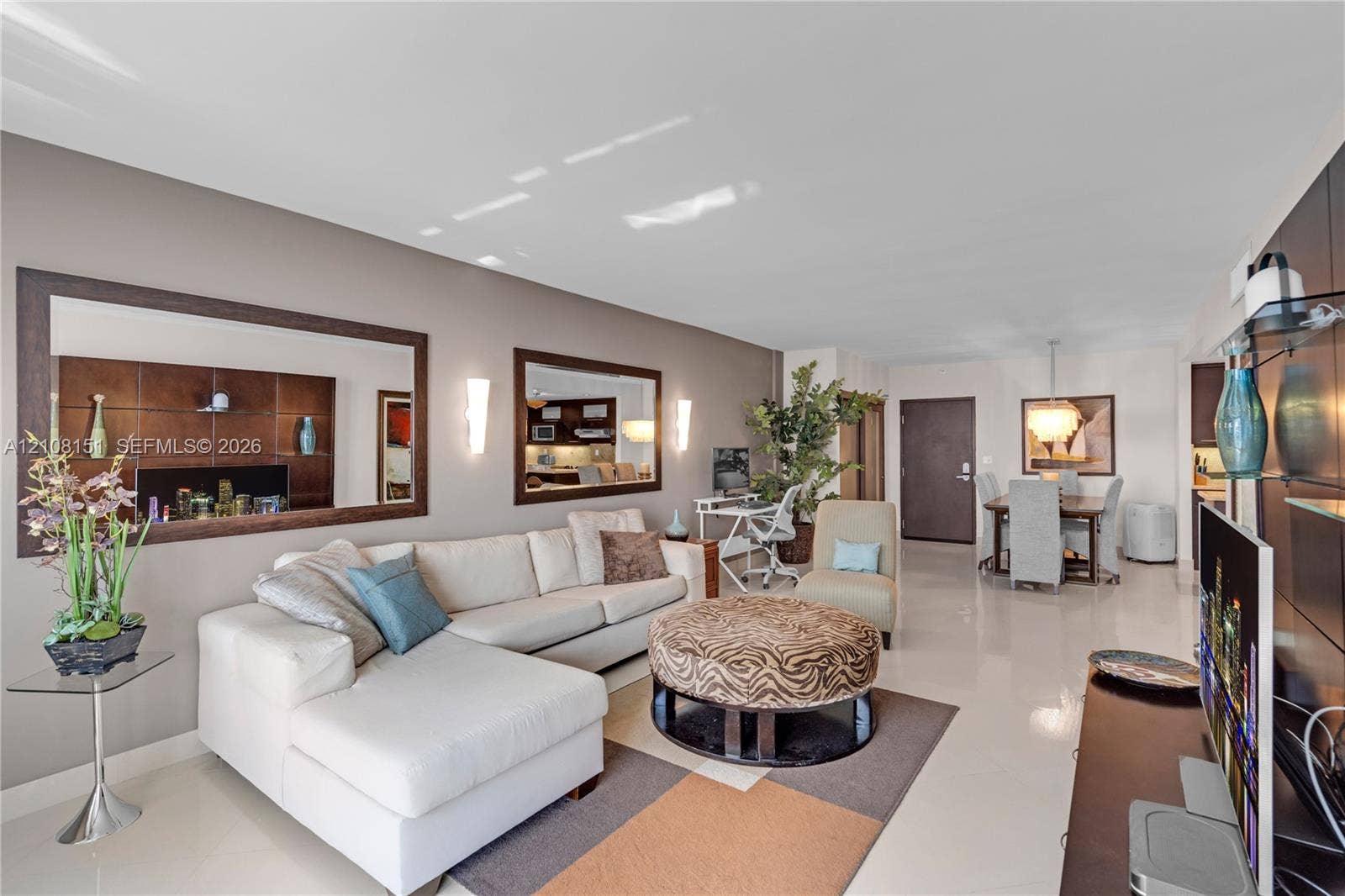 Open-concept interior featuring polished tile flooring, wall-mounted sconce lighting, and dual inset mirrors with dark wood-finish trim