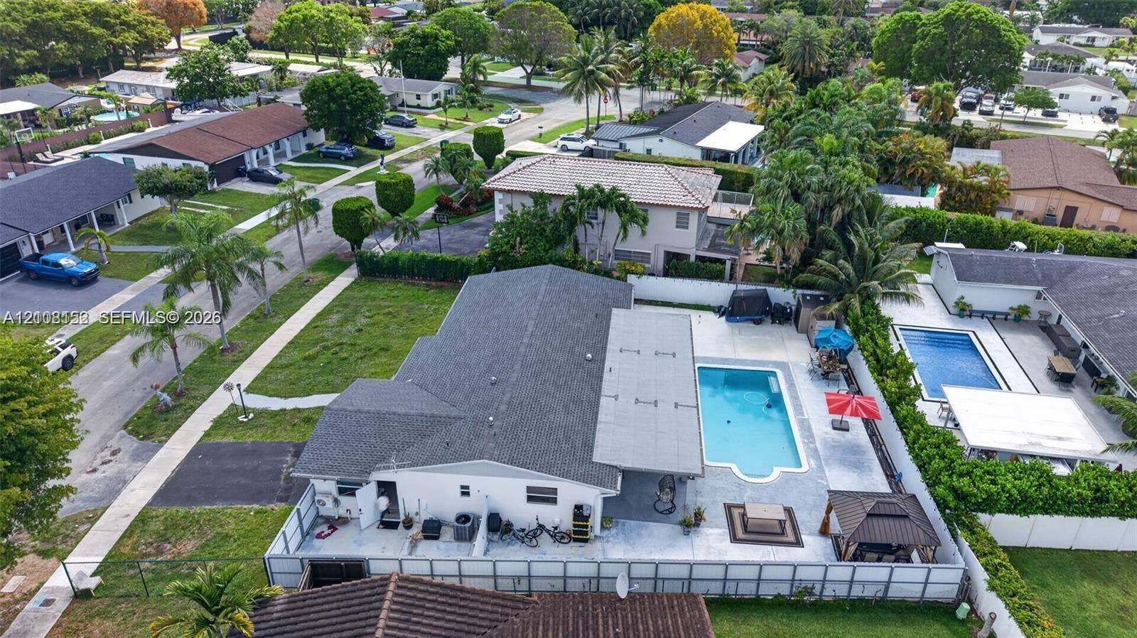 Corner lot property featuring an in-ground swimming pool, expansive concrete patio, and fenced perimeter