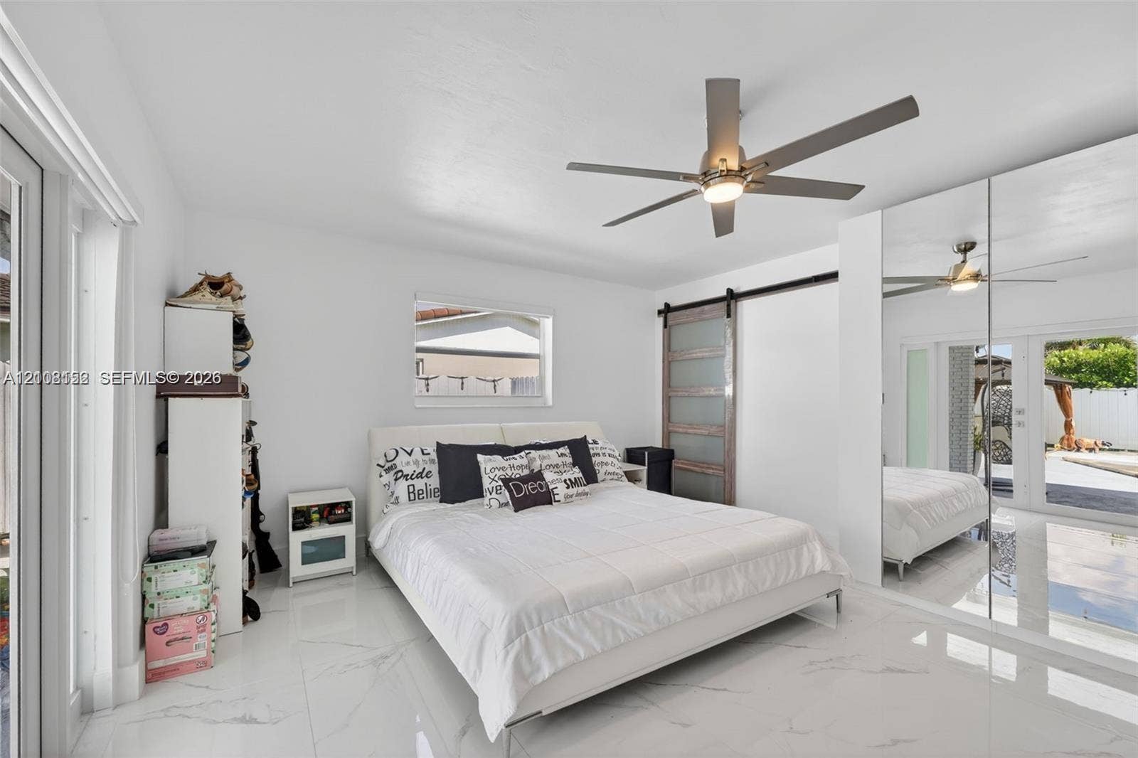 Polished tile flooring, mirrored closet doors, sliding barn-style door, and integrated ceiling fan with light fixture