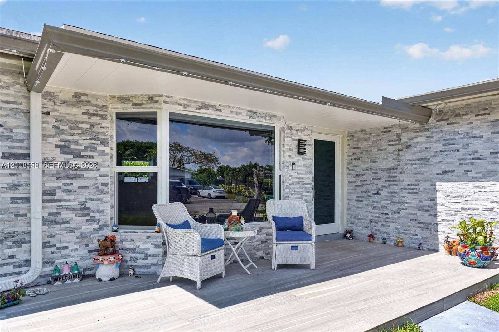 Exterior facade featuring a stacked stone veneer, covered porch with wood-finish decking, and large picture window