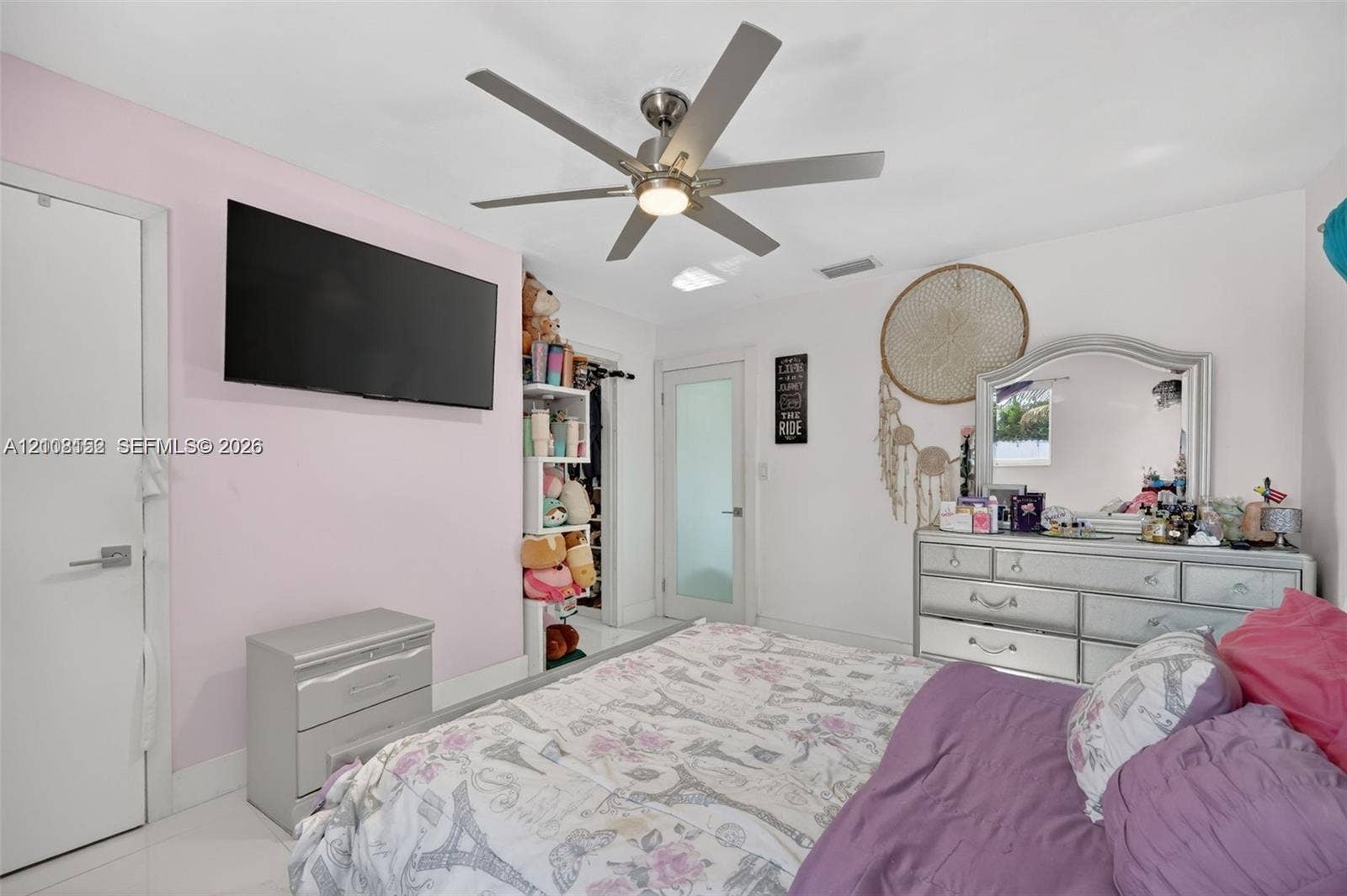 Room featuring a central ceiling fan with integrated lighting, tile flooring, and a door with a frosted glass panel