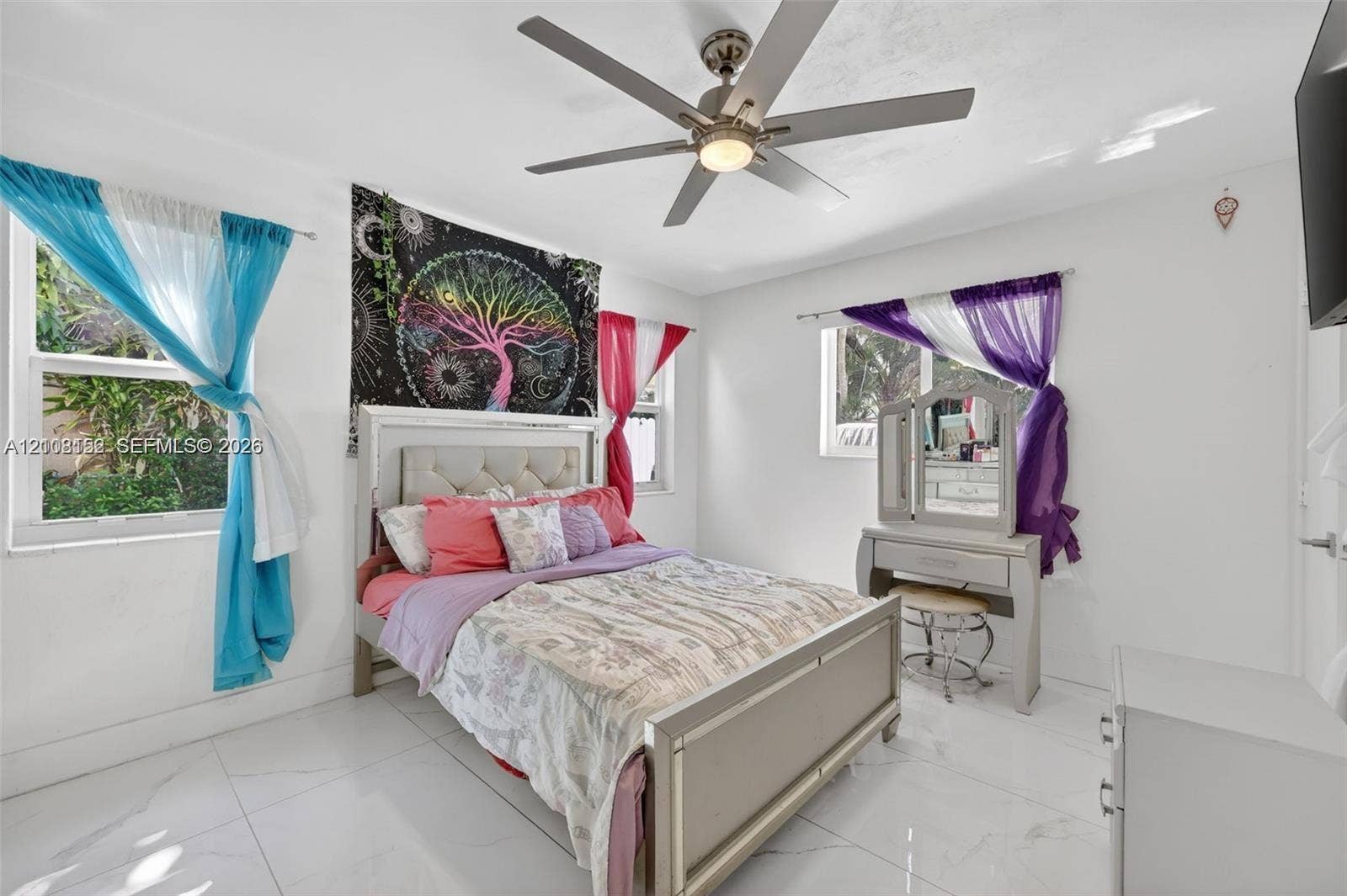 Bedroom featuring large-format light-toned tile flooring, dual windows, and a ceiling fan with integrated lighting