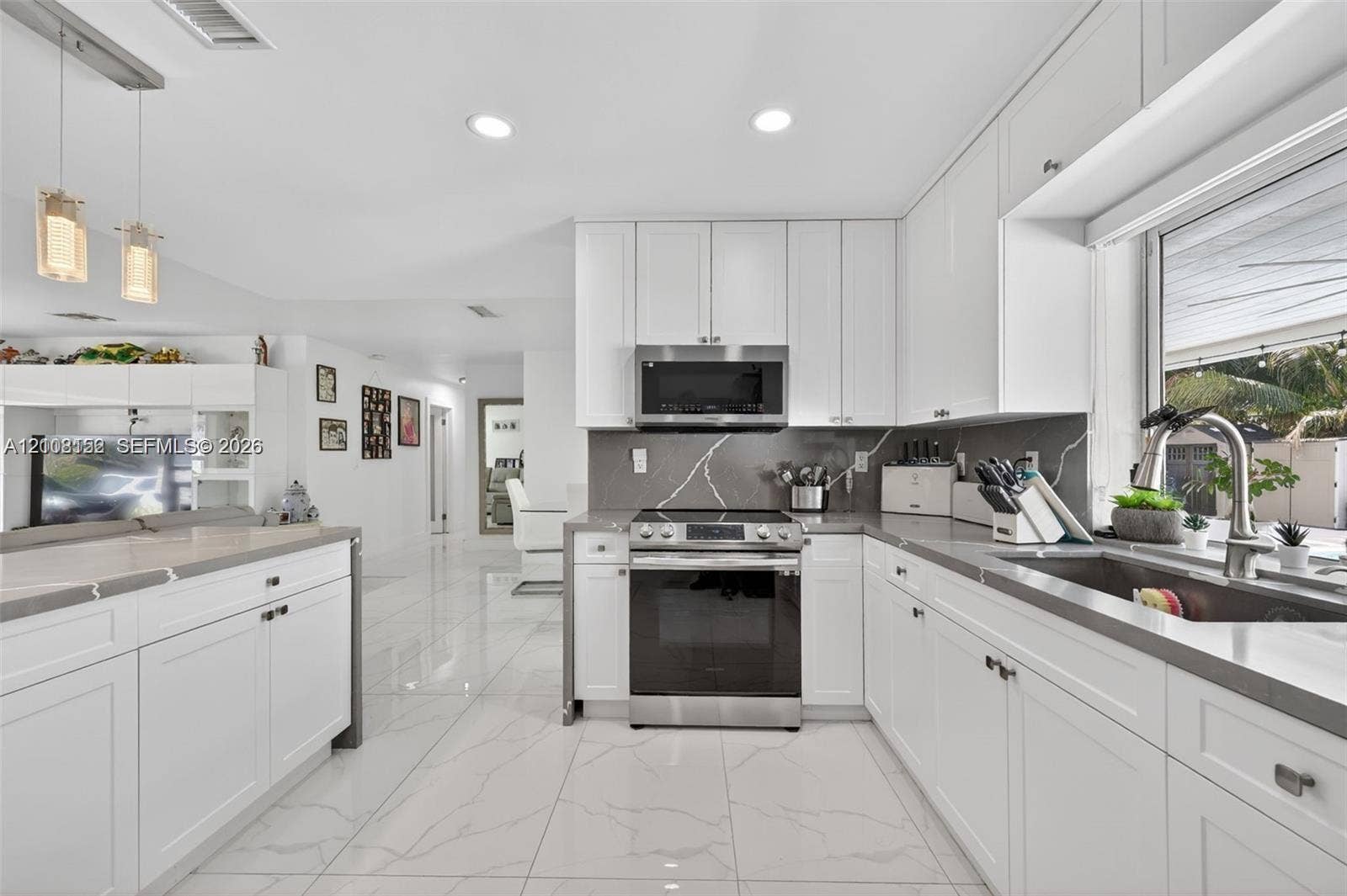 Kitchen featuring white shaker-style cabinetry, solid-surface countertops, tile flooring, recessed lighting, and stainless steel appliances