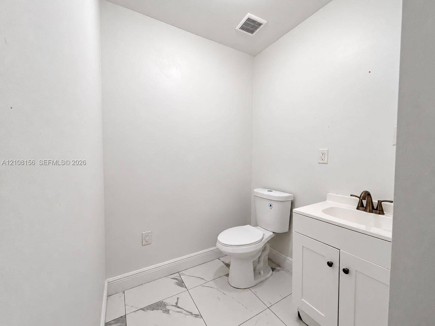 17175 NW 41st Avenue, Miami Gardens, FL 33055 White vanity with a neutral countertop, dark metal faucet, ceramic toilet, and large-format tile flooring with a veined pattern