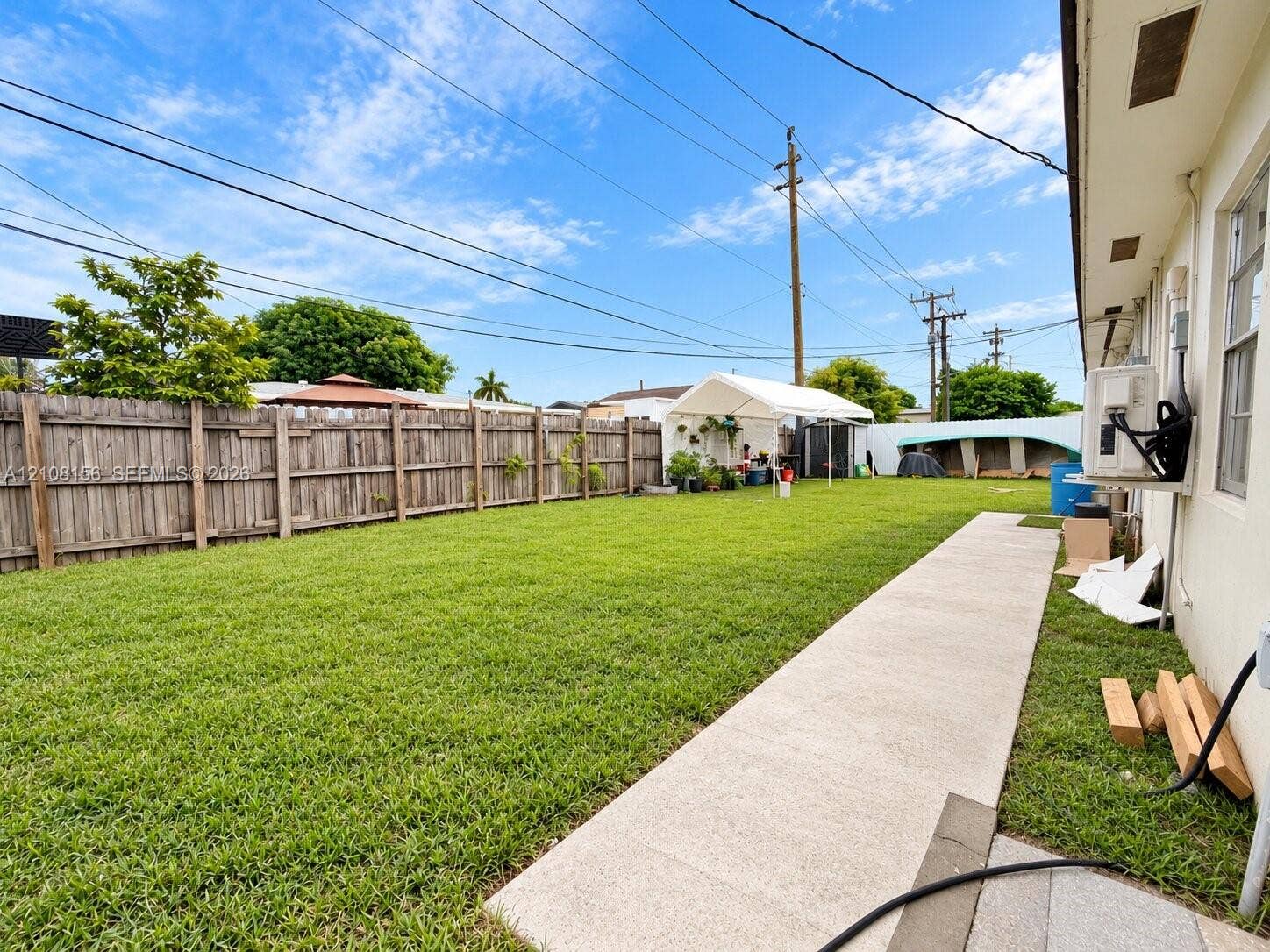 17175 NW 41st Avenue, Miami Gardens, FL 33055 Expansive backyard featuring a level grass lawn, perimeter wood privacy fencing, and a concrete pathway