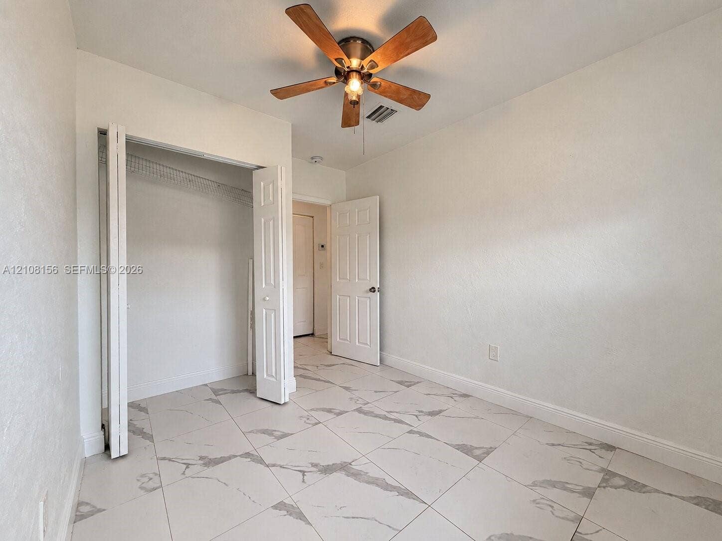 17175 NW 41st Avenue, Miami Gardens, FL 33055 Large-format stone-patterned tile flooring, multi-panel interior door, bifold closet door, and ceiling fan with integrated lighting