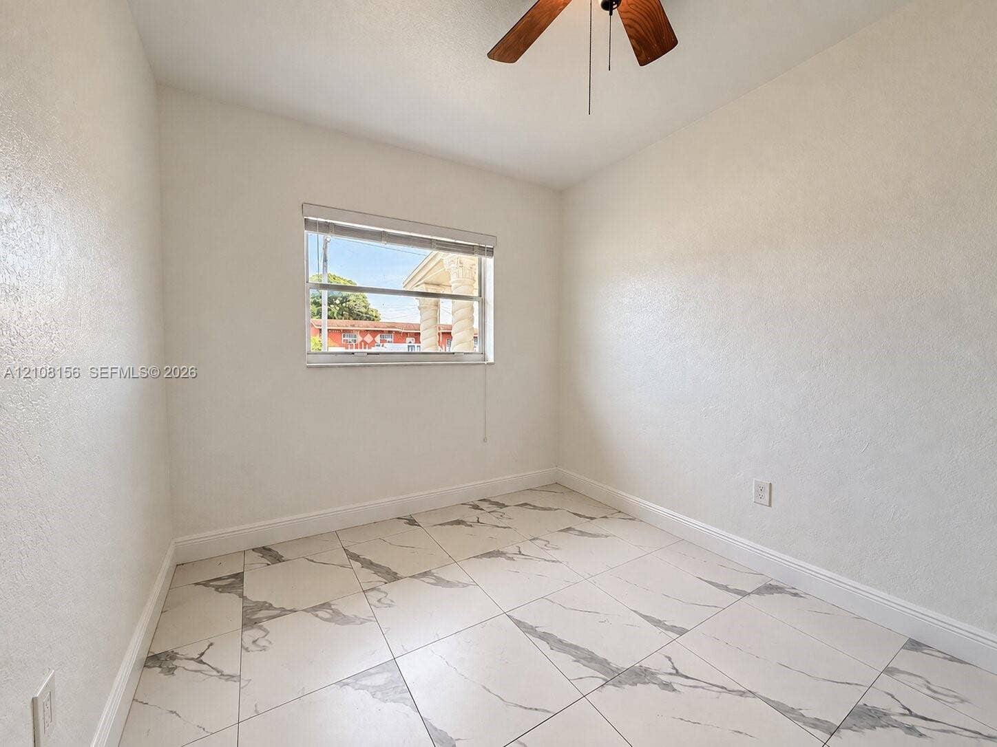 17175 NW 41st Avenue, Miami Gardens, FL 33055 Room featuring large-format tile flooring with a neutral veined pattern, smooth wall finishes, a single-hung window, and a ceiling-mounted fan with wood-finish blades