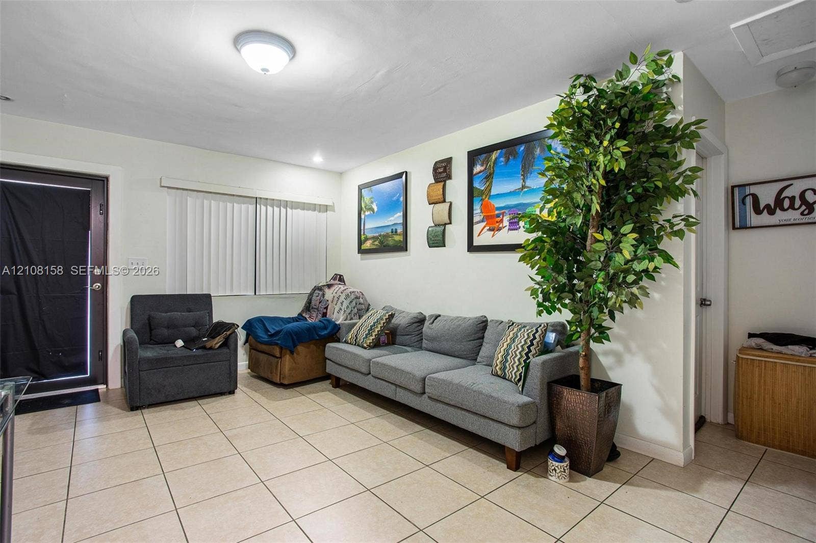 Neutral-toned ceramic tile flooring, flush-mount ceiling lighting, and a glass-paneled exterior entry door with vertical blinds