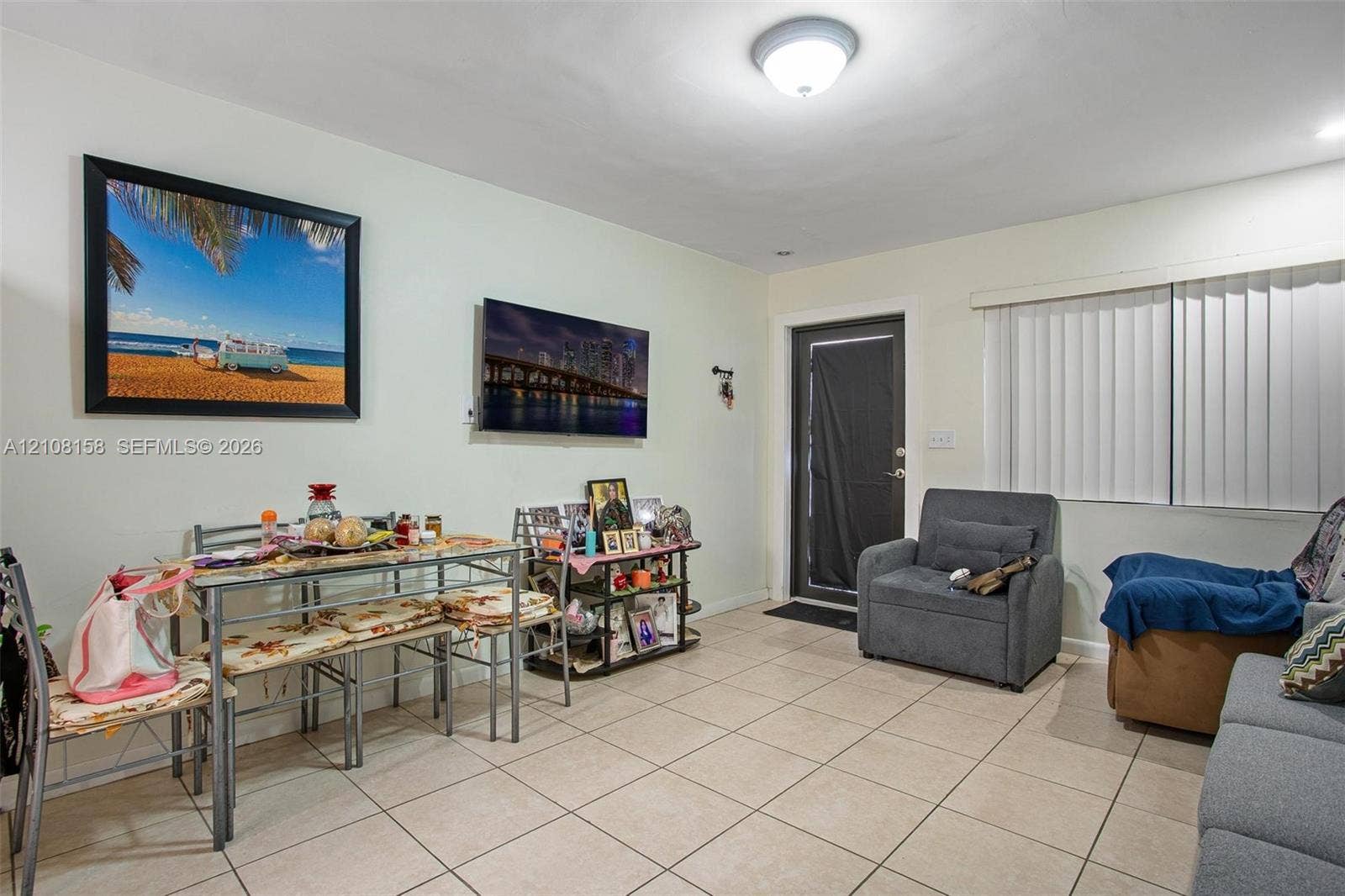 Neutral-toned ceramic tile flooring, ceiling-mounted light fixture, and vertical window blinds