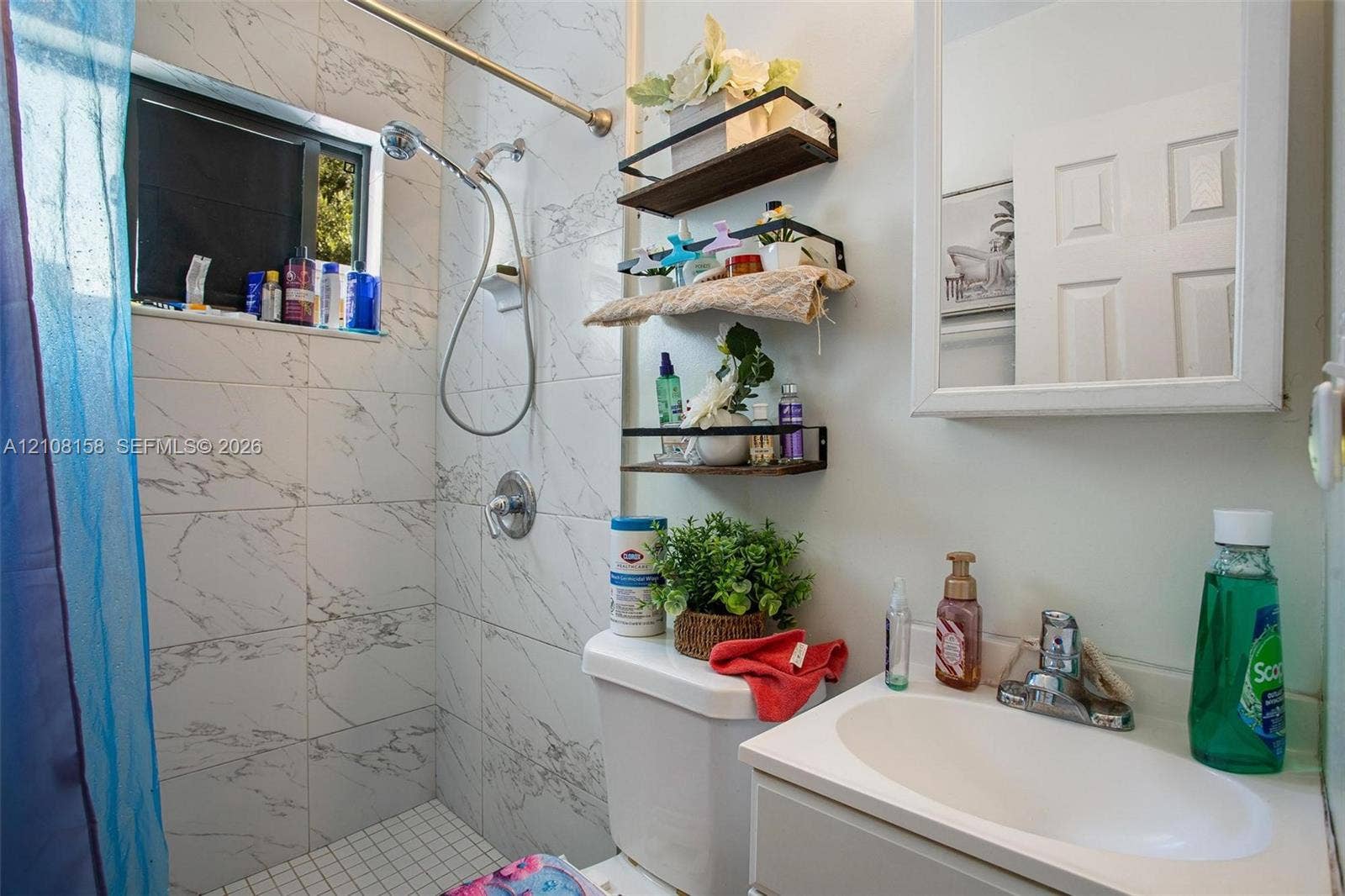 Bathroom featuring floor-to-ceiling stone-patterned tile, white vanity with integrated oval sink, chrome-finished hardware, and recessed medicine cabinet