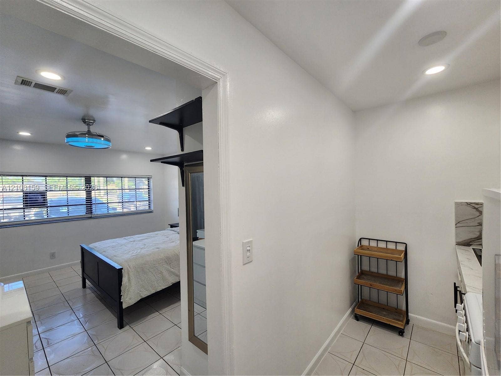 Interior space featuring neutral wall tones, large-format tile flooring, recessed ceiling lighting, and built-in shelving