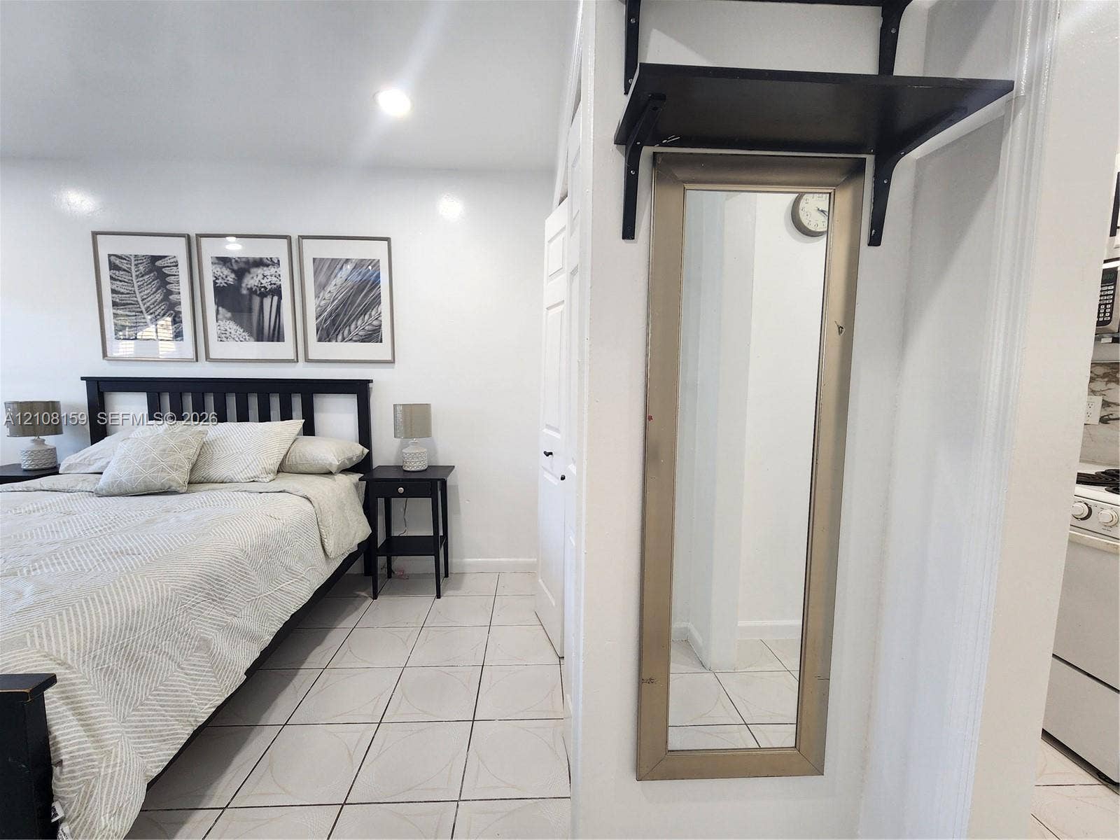 Interior space featuring white tile flooring, recessed ceiling lighting, and a wall-mounted shelving unit