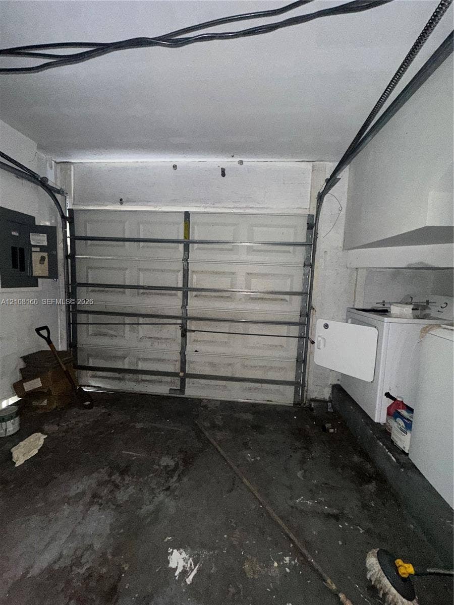 1262 NW 126th Avenue, Sunrise, FL 33323 Enclosed garage space featuring a paneled sectional garage door, concrete flooring, and an integrated electrical service panel