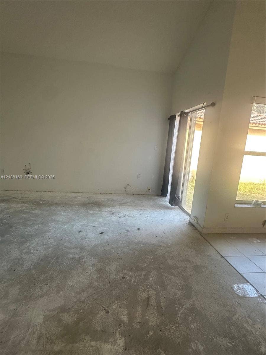 1262 NW 126th Avenue, Sunrise, FL 33323 High-ceiling interior featuring a sliding glass door and windows with horizontal blinds