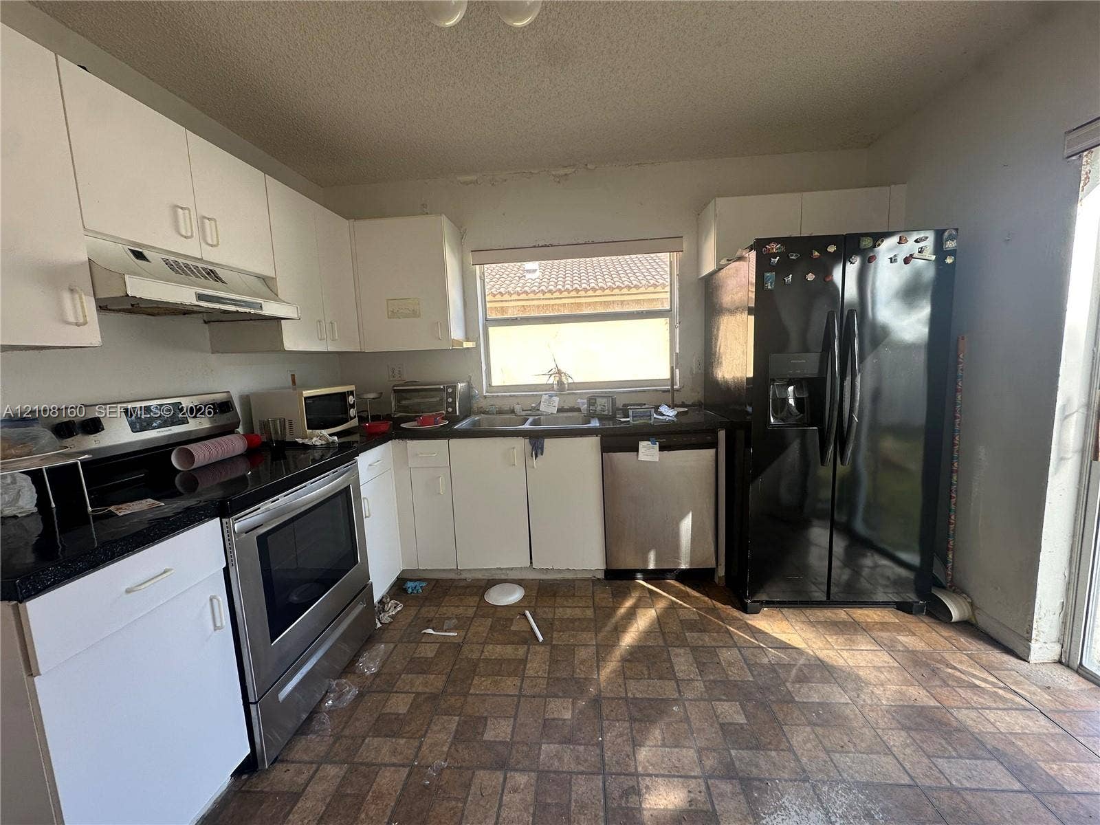 1262 NW 126th Avenue, Sunrise, FL 33323 Kitchen featuring white cabinetry, dark countertops, a stainless steel range and dishwasher, and a black refrigerator