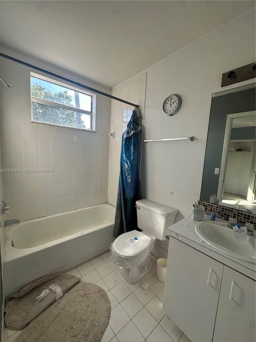 1262 NW 126th Avenue, Sunrise, FL 33323 Bathroom featuring white tiled tub surround, rectangular window, vanity with integrated basin, mosaic tile backsplash, and wall-mounted vanity mirror