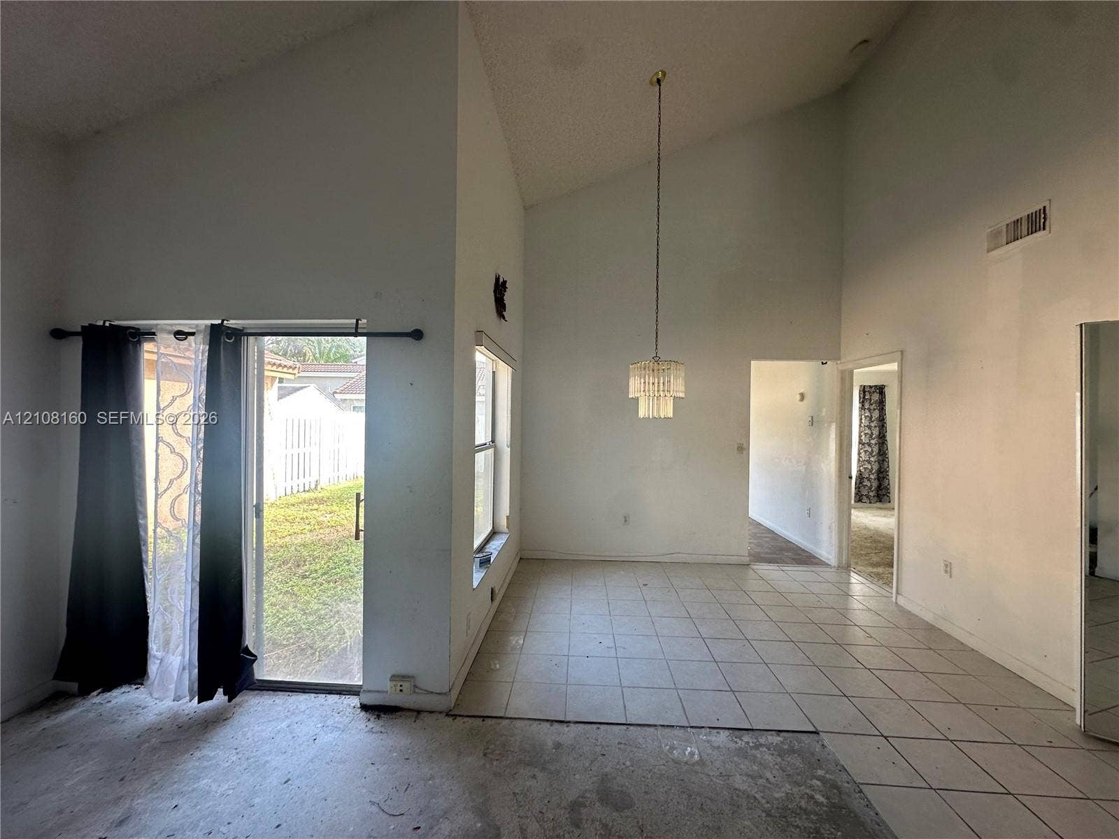 1262 NW 126th Avenue, Sunrise, FL 33323 Vaulted ceilings featuring a suspended tiered chandelier, large window, and sliding glass door with exterior access