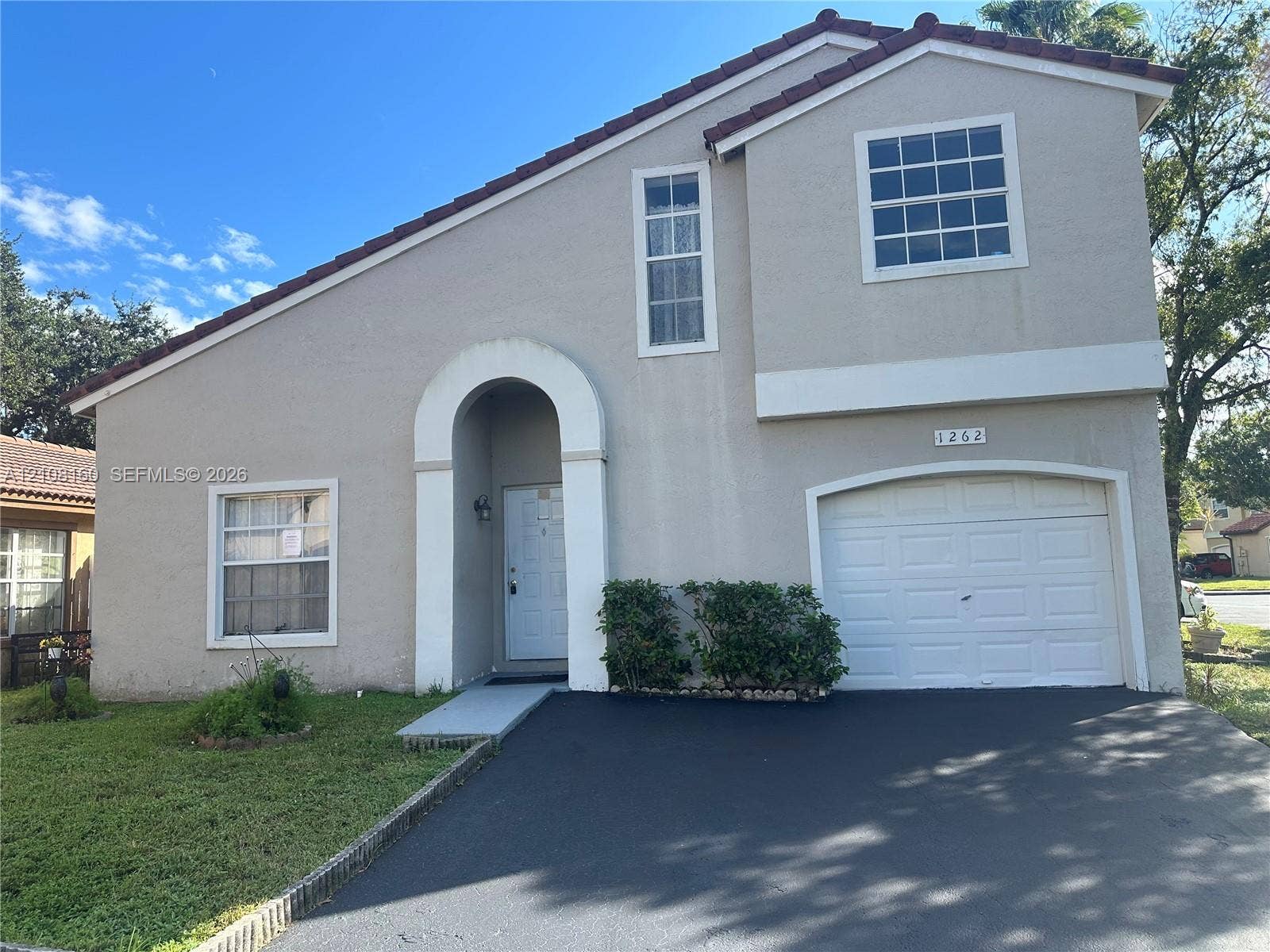 1262 NW 126th Avenue, Sunrise, FL 33323 Two-story exterior featuring a stucco facade, tiled roof, arched entryway, and an attached single-car garage