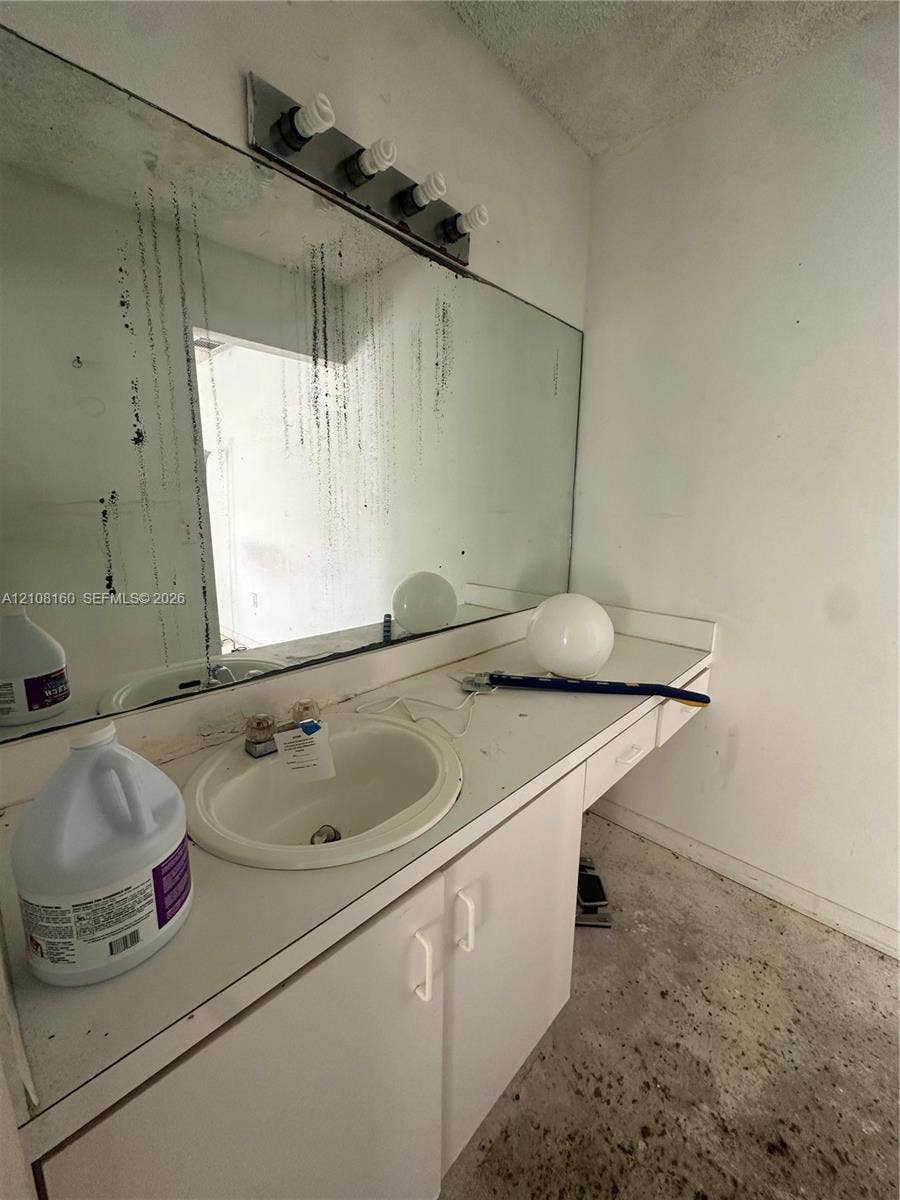 1262 NW 126th Avenue, Sunrise, FL 33323 Vanity featuring an integrated sink, built-in cabinetry, and a full-width wall-mounted mirror with an attached four-light fixture