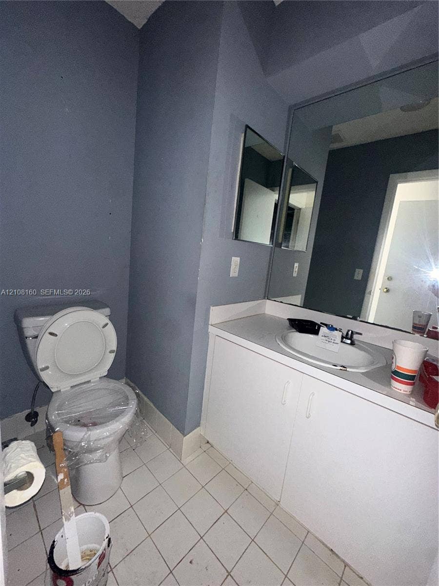 1262 NW 126th Avenue, Sunrise, FL 33323 Bathroom featuring a white vanity cabinet, solid-surface countertop with an integrated oval sink, single-handle faucet, large wall-mounted mirror, and tile flooring