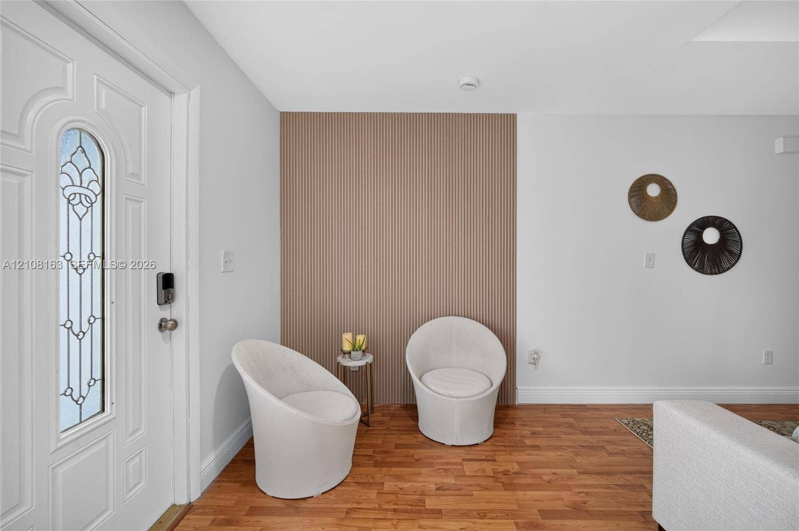 11510 SW 5th Street, #1, Sweetwater, Sweetwater, FL 33174 Entryway featuring a front door with decorative glass insert, wood-finish flooring, and a floor-to-ceiling vertical slatted wood-finish accent wall
