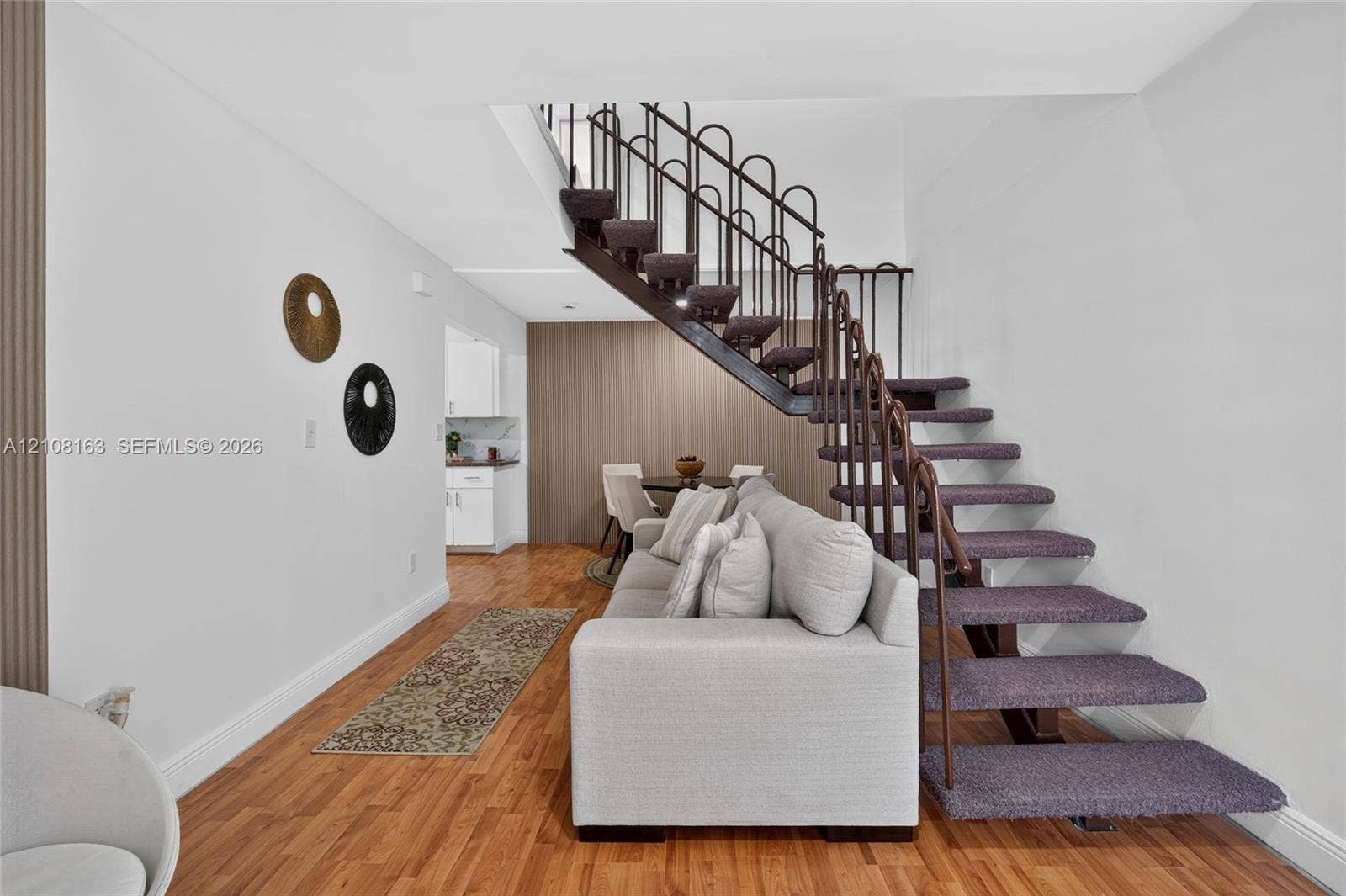 11510 SW 5th Street, #1, Sweetwater, Sweetwater, FL 33174 Open-riser staircase with carpeted treads and decorative metal railing, wood-finish flooring, and vertical accent paneling