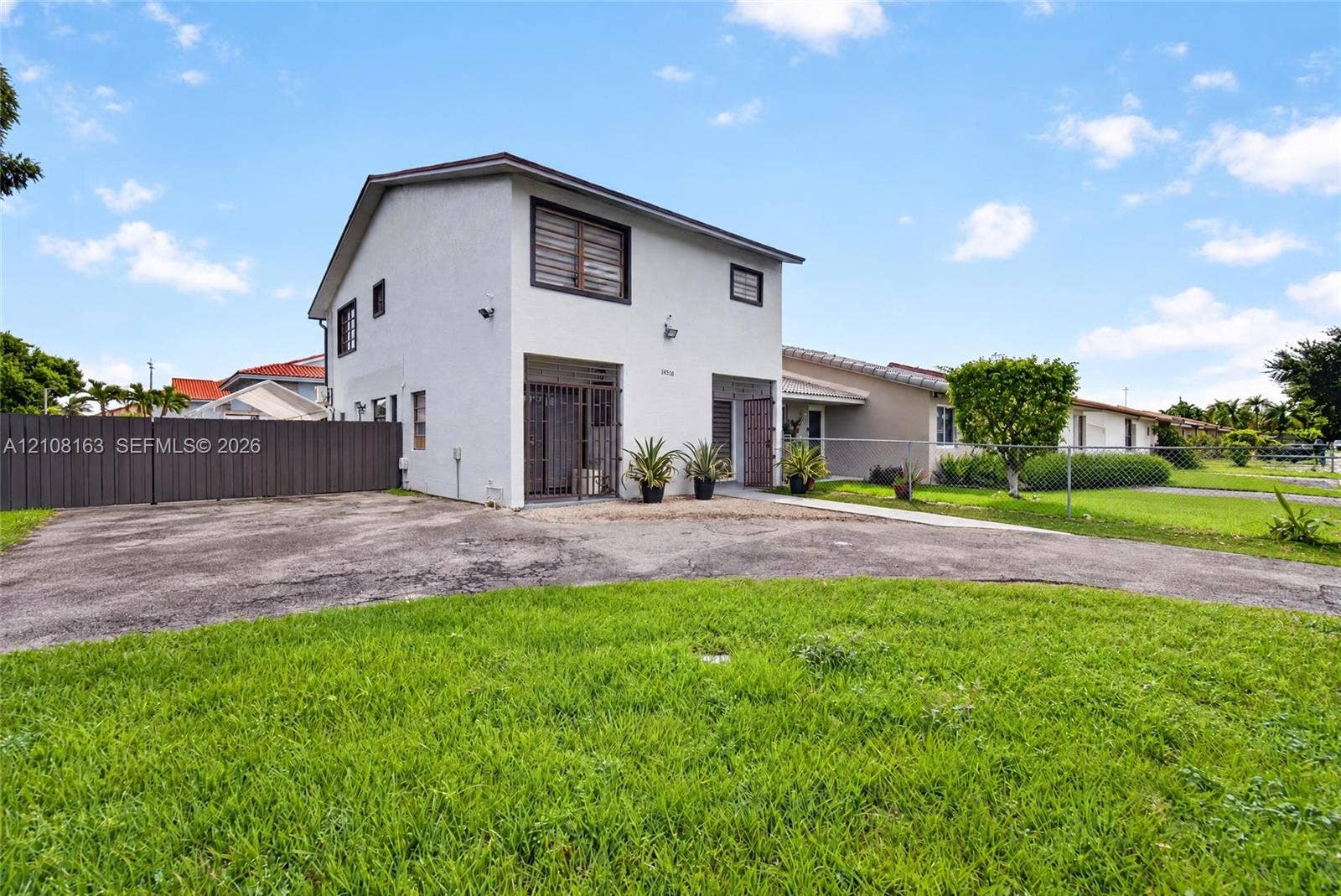 11510 SW 5th Street, #1, Sweetwater, Sweetwater, FL 33174 Two-story exterior featuring a light-toned stucco facade, dual ground-level entryways with metal security gates, and a paved asphalt driveway