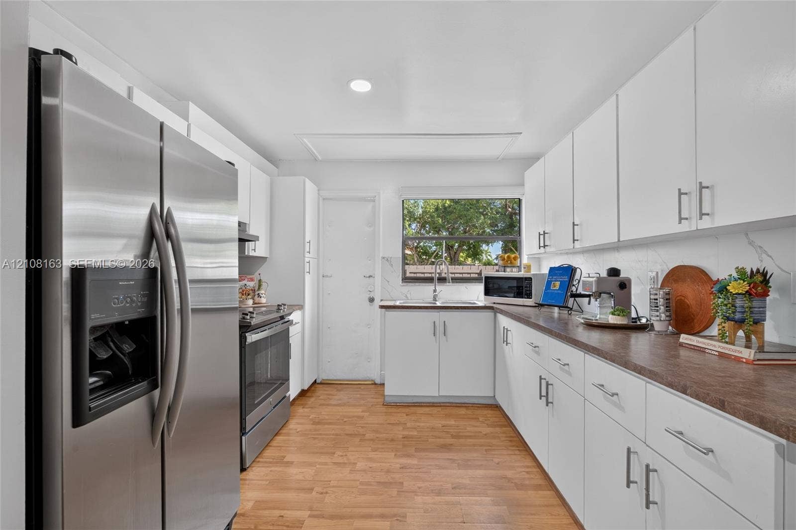 11510 SW 5th Street, #1, Sweetwater, Sweetwater, FL 33174 Kitchen featuring white cabinetry, wood-finish flooring, stainless steel appliances, and a rectangular undermount sink with a gooseneck faucet