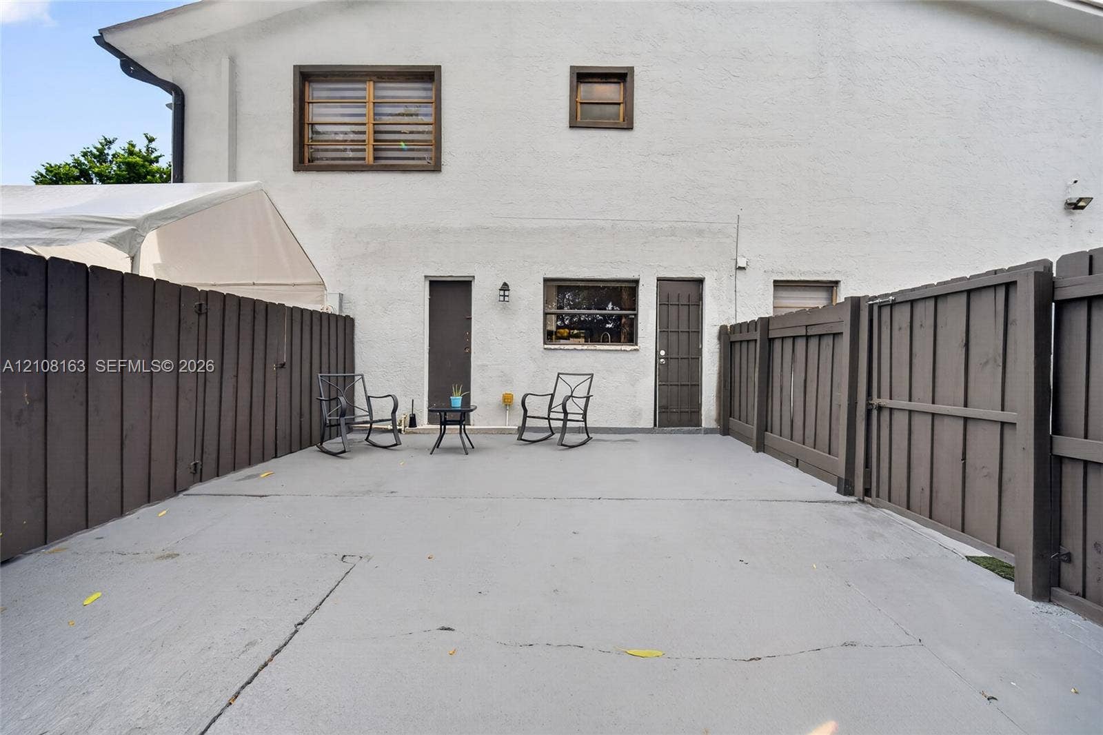 11510 SW 5th Street, #1, Sweetwater, Sweetwater, FL 33174 Stucco exterior featuring a concrete patio, wood-style privacy fencing, and exterior wall-mounted lighting