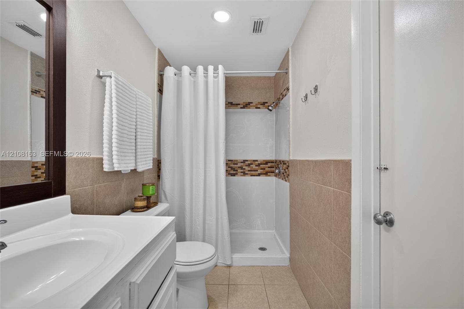 11510 SW 5th Street, #1, Sweetwater, Sweetwater, FL 33174 Bathroom featuring a white vanity with a porcelain sink, beige wall tiling, mosaic tile accent border, and a walk-in shower with white surround
