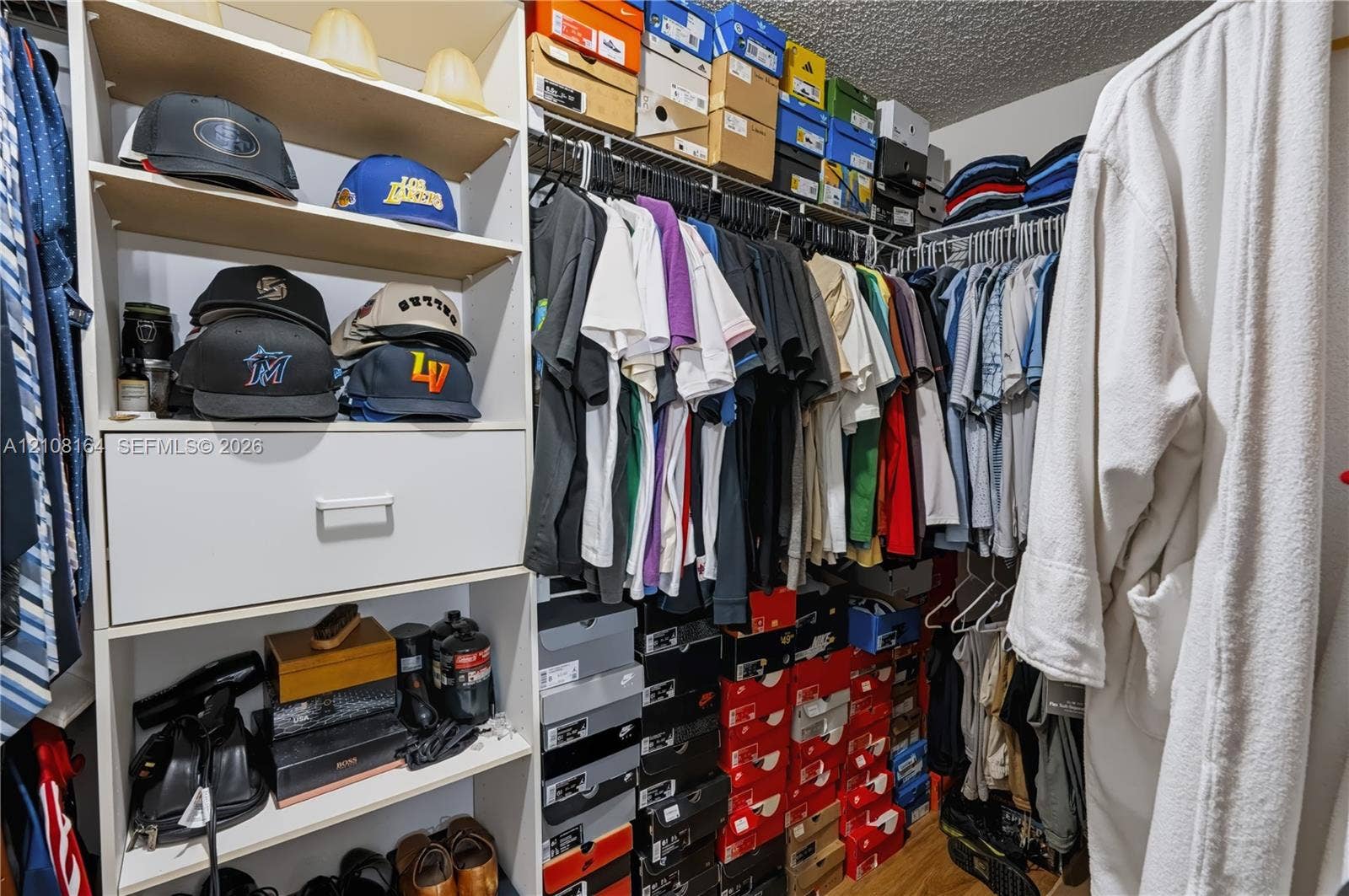 3983 NW 122nd Terrace, Sunrise, FL 33323 Walk-in closet featuring white laminate built-in cabinetry, an integrated pull-out drawer, adjustable open shelving, and multi-level metal hanging rods