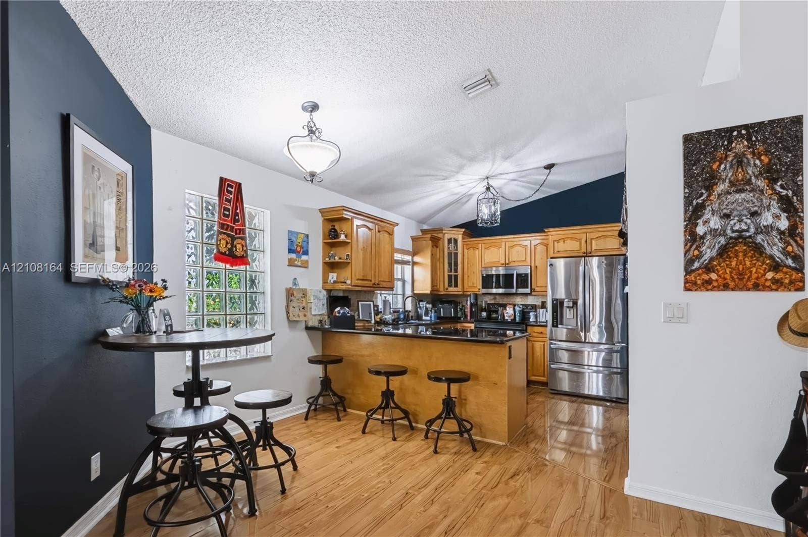 3983 NW 122nd Terrace, Sunrise, FL 33323 Kitchen featuring wood cabinetry, dark stone countertops, stainless steel appliances, wood-finish flooring, and a decorative glass block window