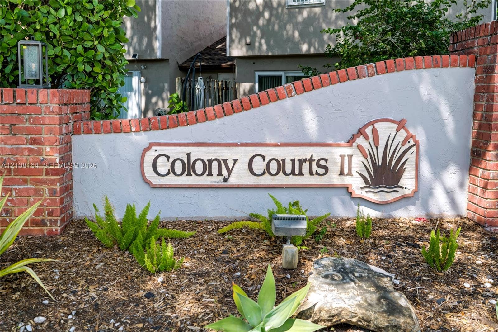 3983 NW 122nd Terrace, Sunrise, FL 33323 Stucco monument sign featuring brick pillars, integrated landscape lighting, and curated garden beds