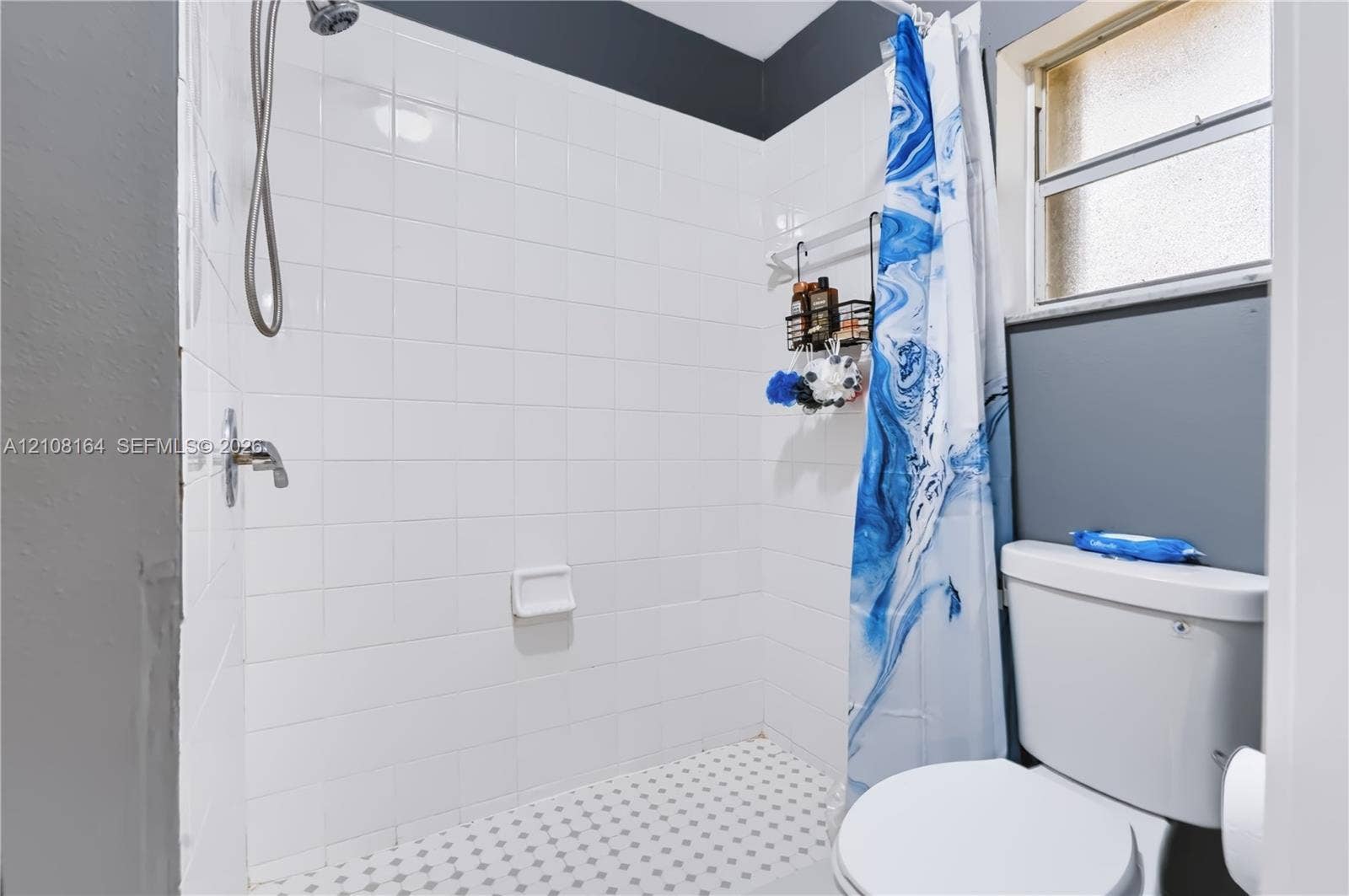 3983 NW 122nd Terrace, Sunrise, FL 33323 Full-height white tile shower enclosure with integrated soap dish, chrome shower hardware, patterned mosaic tile flooring, and standard-height toilet