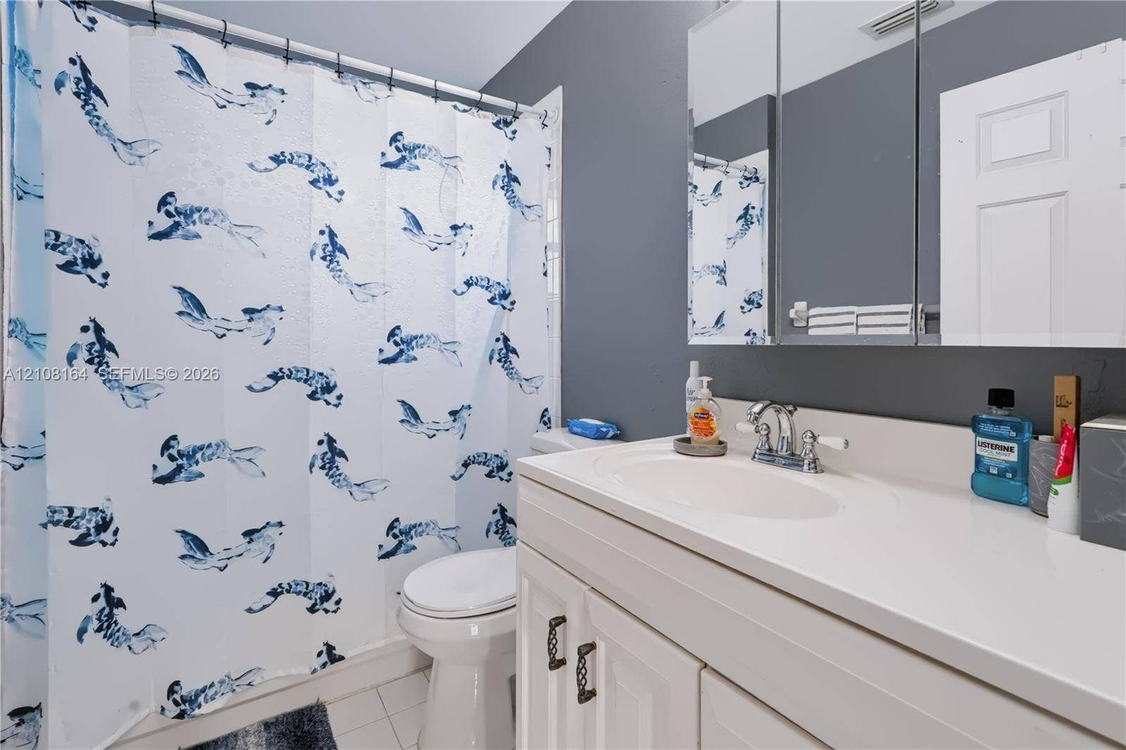 3983 NW 122nd Terrace, Sunrise, FL 33323 White vanity with an integrated countertop sink, chrome dual-handle faucet, and mirrored medicine cabinet