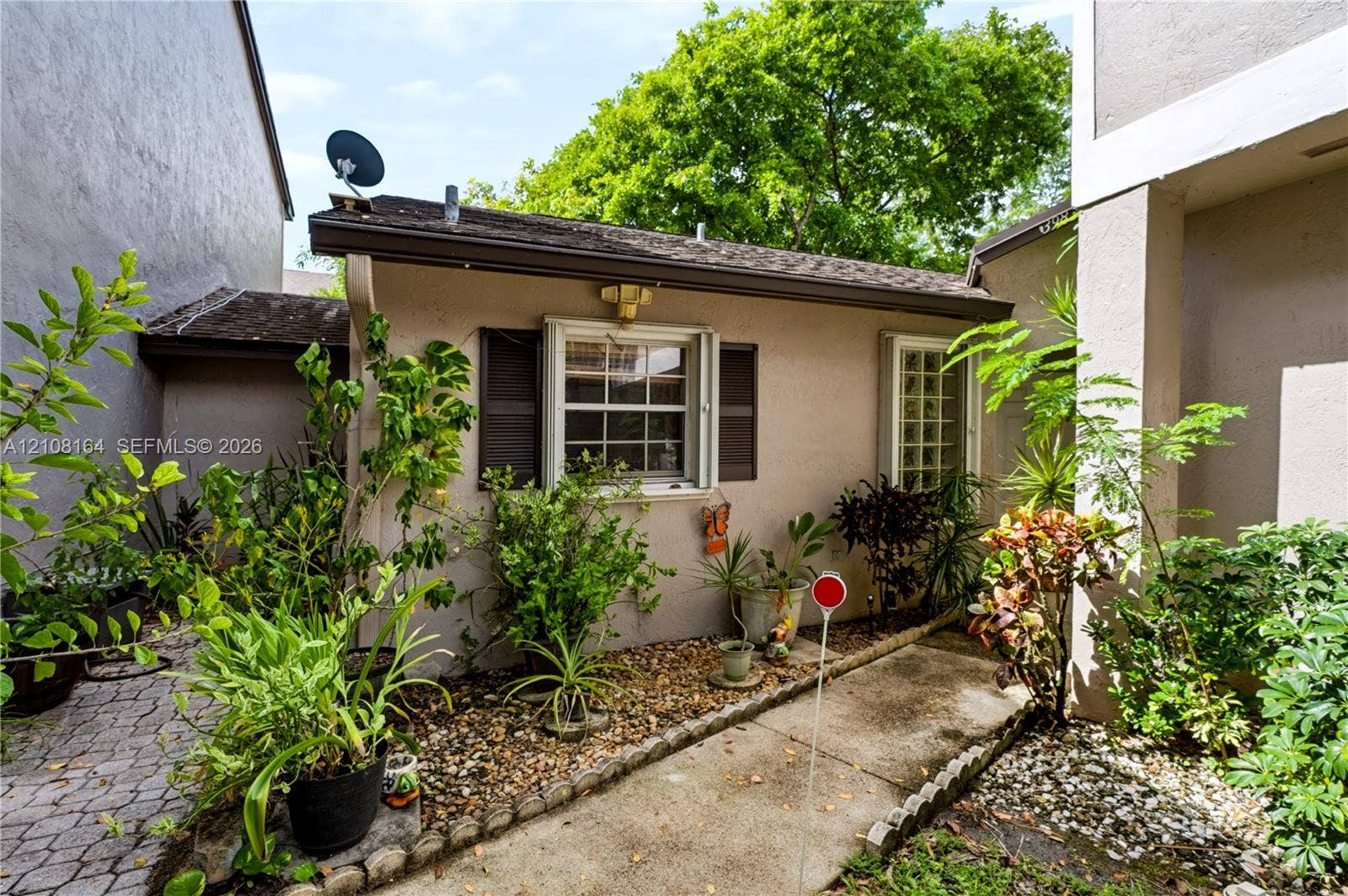 3983 NW 122nd Terrace, Sunrise, FL 33323 Stucco exterior featuring dual-pane windows, dark shutter accents, exterior lighting, and a stone-paver walkway
