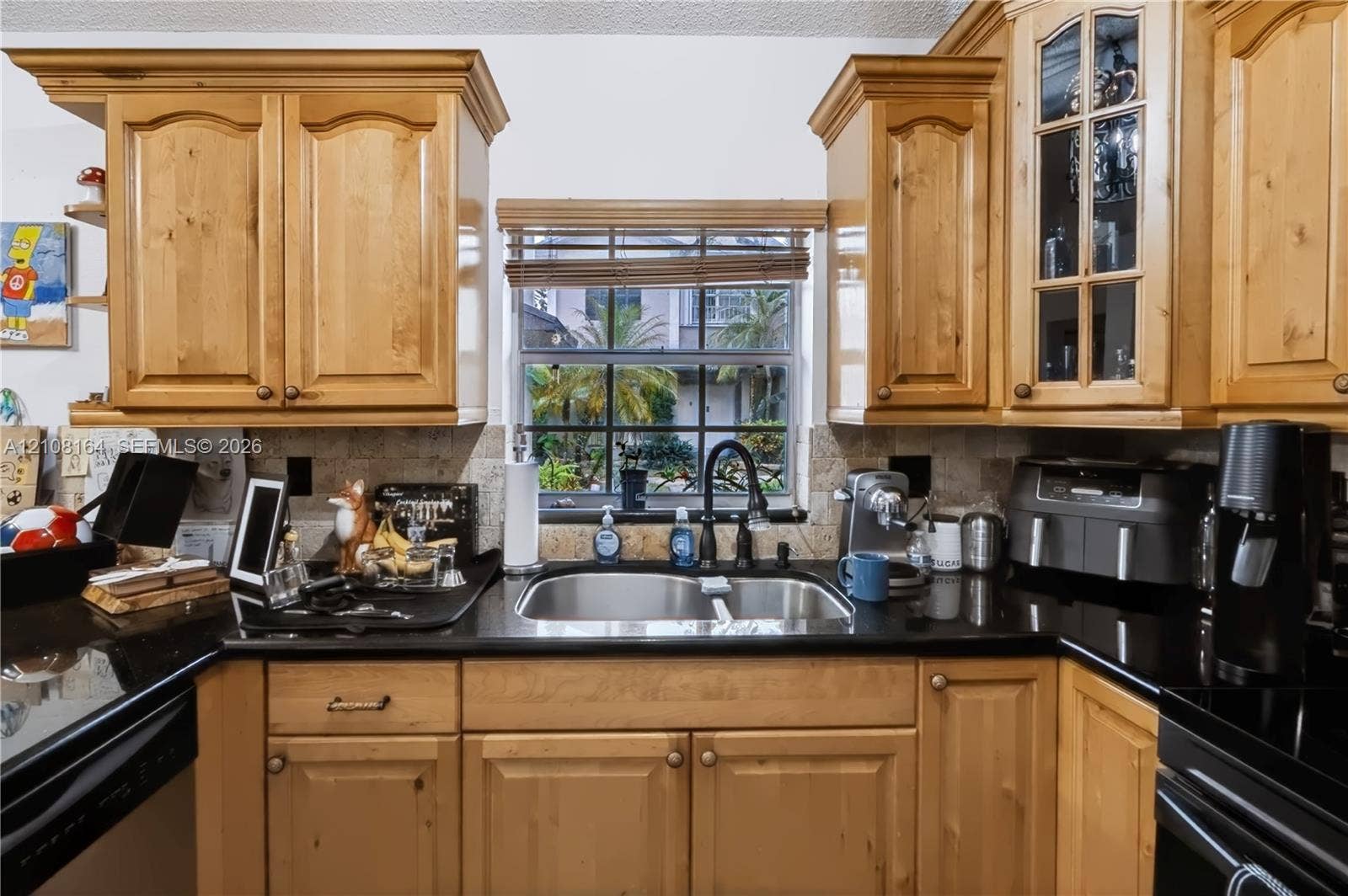 3983 NW 122nd Terrace, Sunrise, FL 33323 Kitchen featuring natural wood cabinetry with crown molding, black stone countertops, stone-tile backsplash, and glass-paneled upper cabinet doors