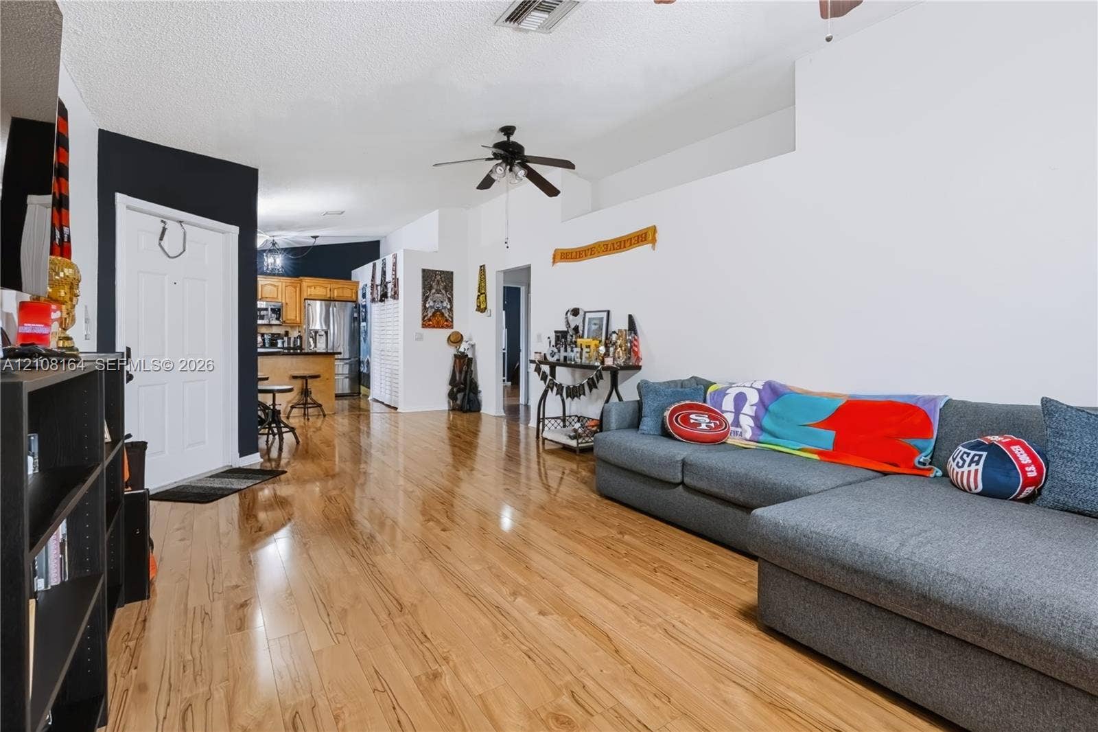 3983 NW 122nd Terrace, Sunrise, FL 33323 High-gloss wood-finish flooring, vaulted ceilings, and a ceiling fan, featuring a kitchen with wood cabinetry and an island
