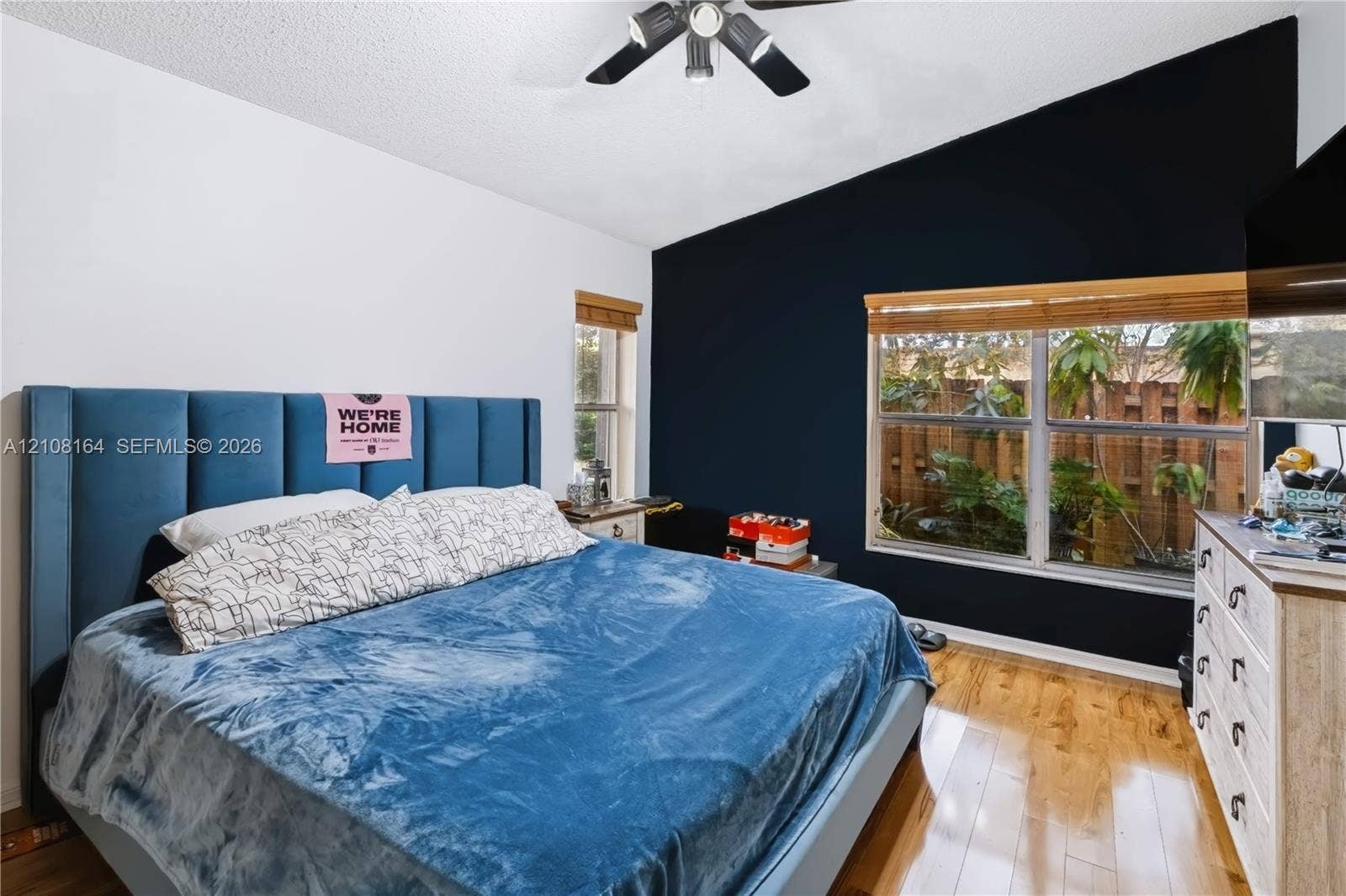 3983 NW 122nd Terrace, Sunrise, FL 33323 Room featuring a vaulted ceiling, wood-finish flooring, dual-pane windows, and a multi-blade ceiling fan with integrated lighting