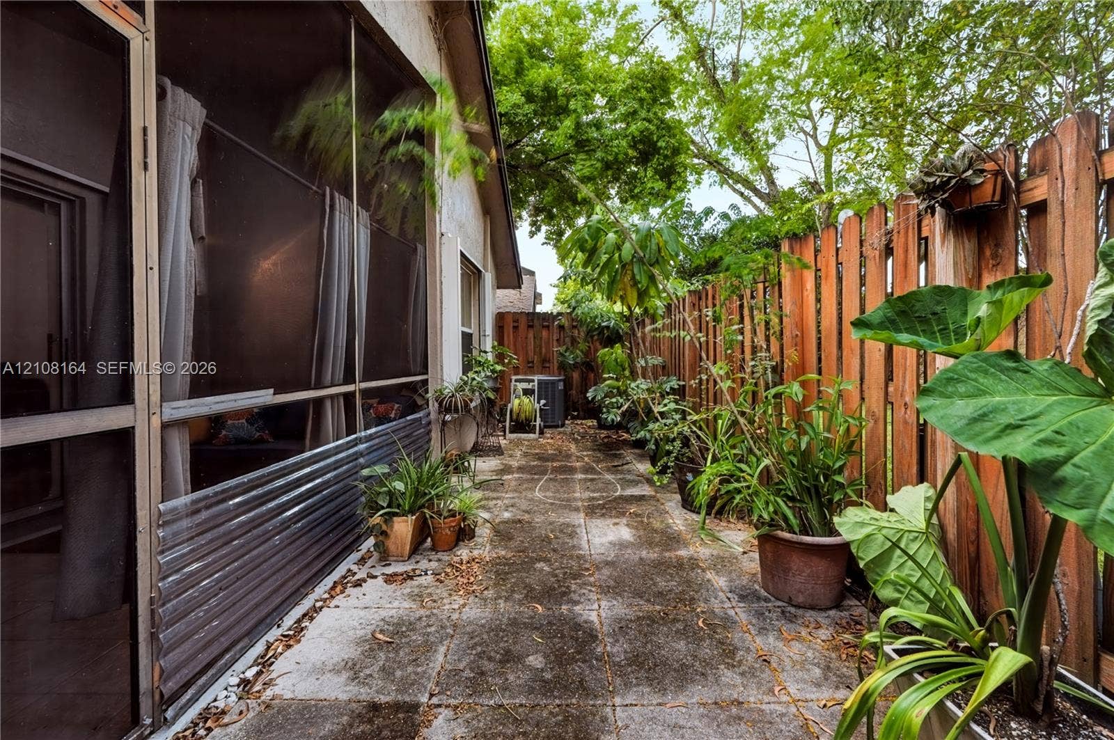 3983 NW 122nd Terrace, Sunrise, FL 33323 Outdoor patio featuring concrete pavers, a screened-in enclosure, and a wood privacy fence