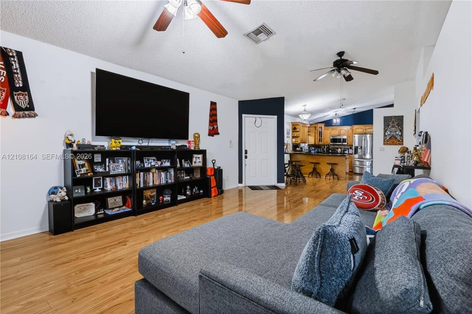 3983 NW 122nd Terrace, Sunrise, FL 33323 Open-concept interior featuring wood-finish flooring, vaulted ceilings, and dual ceiling fans