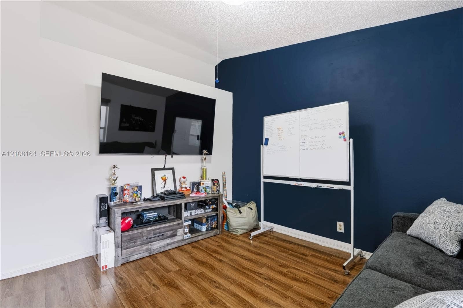 3983 NW 122nd Terrace, Sunrise, FL 33323 Wood-finish flooring and a high-contrast accent wall featuring a deep navy finish