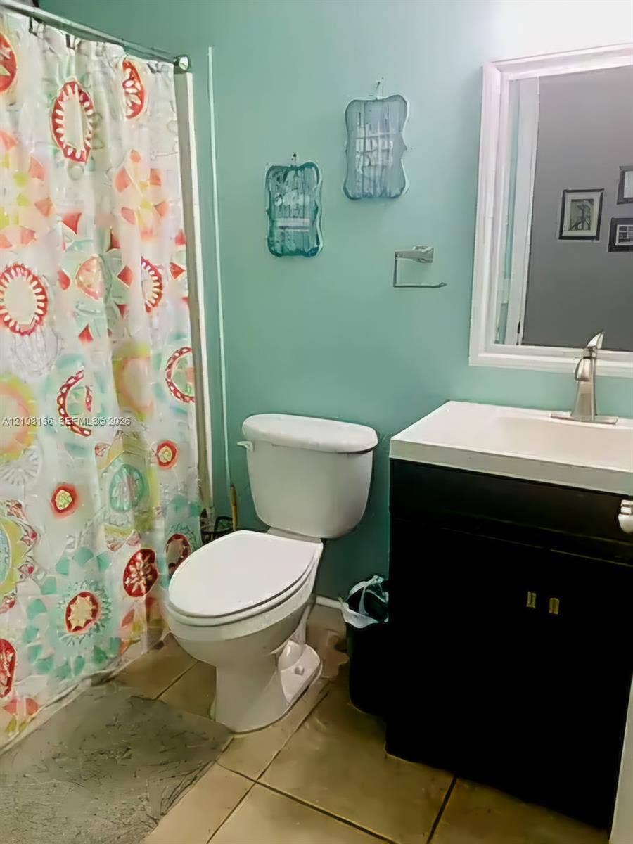 Bathroom featuring a vanity with an integrated rectangular sink, single-handle chrome faucet, wall-mounted mirror, and ceramic tile flooring