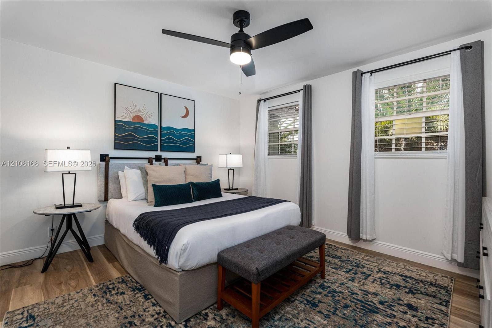 Wood-finish flooring, dual windows with multi-pane glass, and a modern matte black ceiling fan with integrated lighting