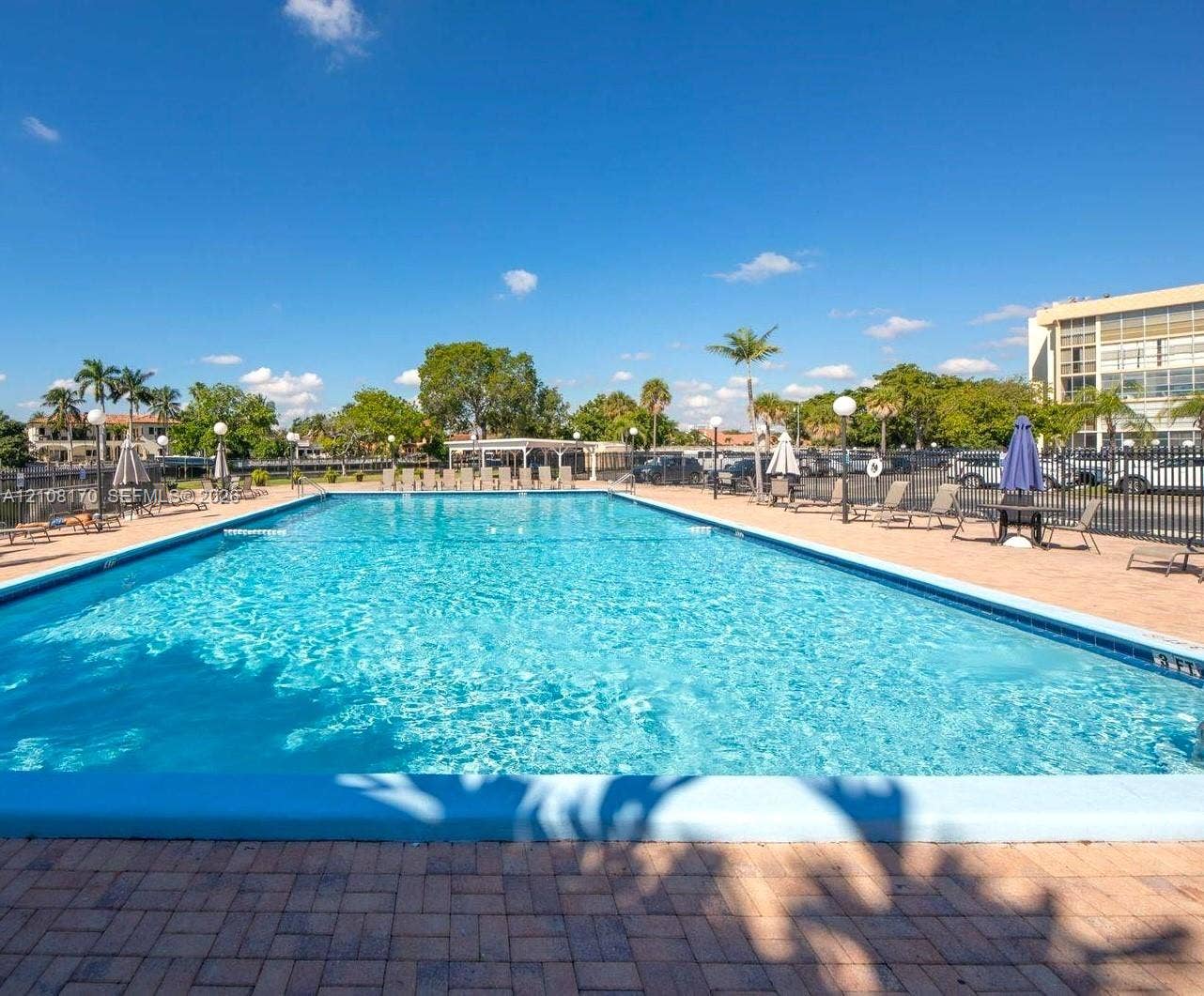 801 Three Islands Boulevard, #108, Hallandale Beach, FL 33009 Rectangular in-ground swimming pool with a stone paver deck and metal perimeter fencing