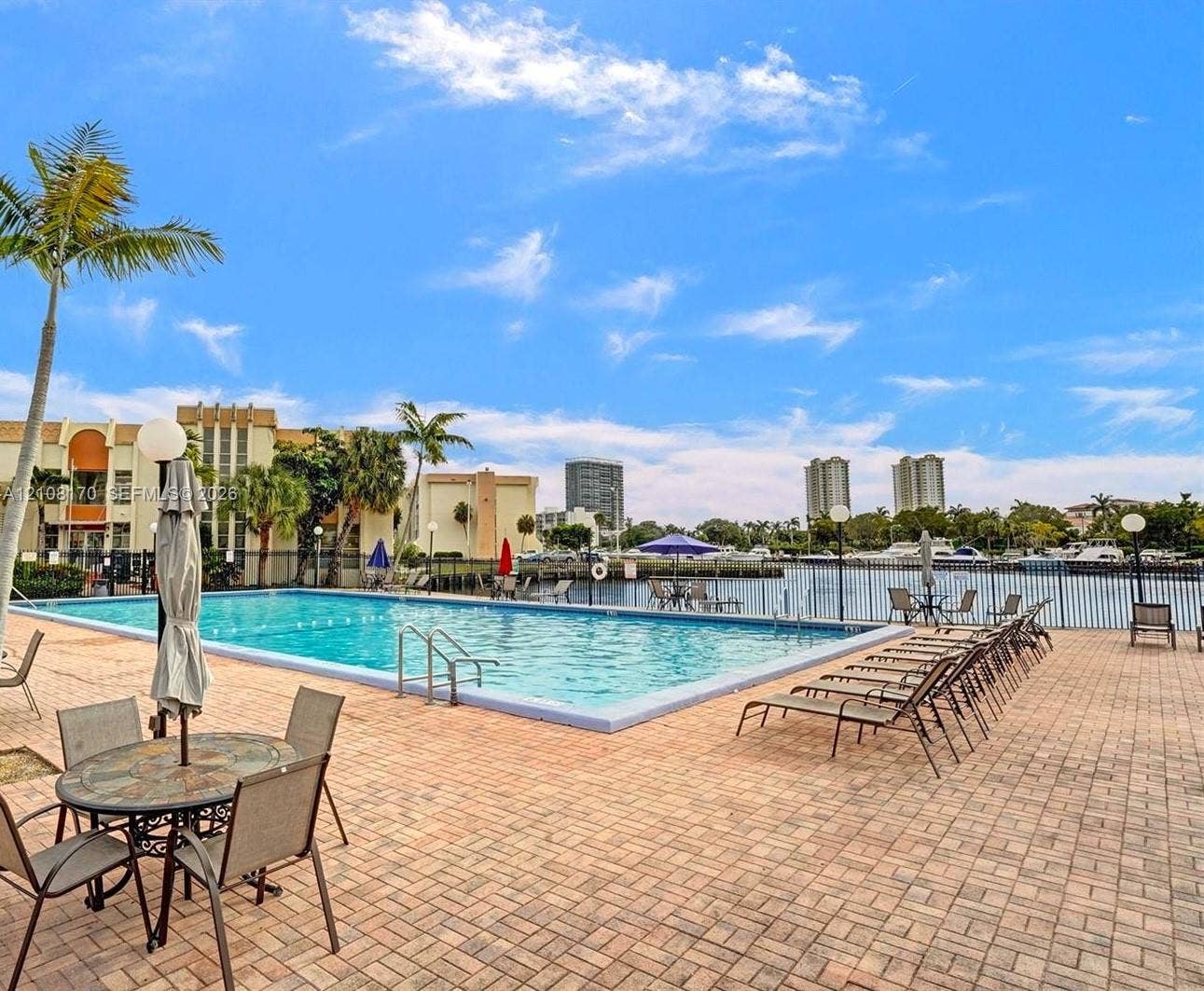 801 Three Islands Boulevard, #108, Hallandale Beach, FL 33009 In-ground swimming pool with metal fencing, brick paver decking, and waterfront access