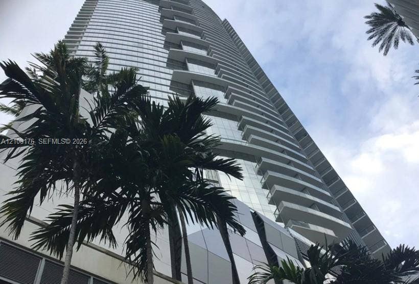 High-rise residential tower featuring a glass facade and tiered private balconies