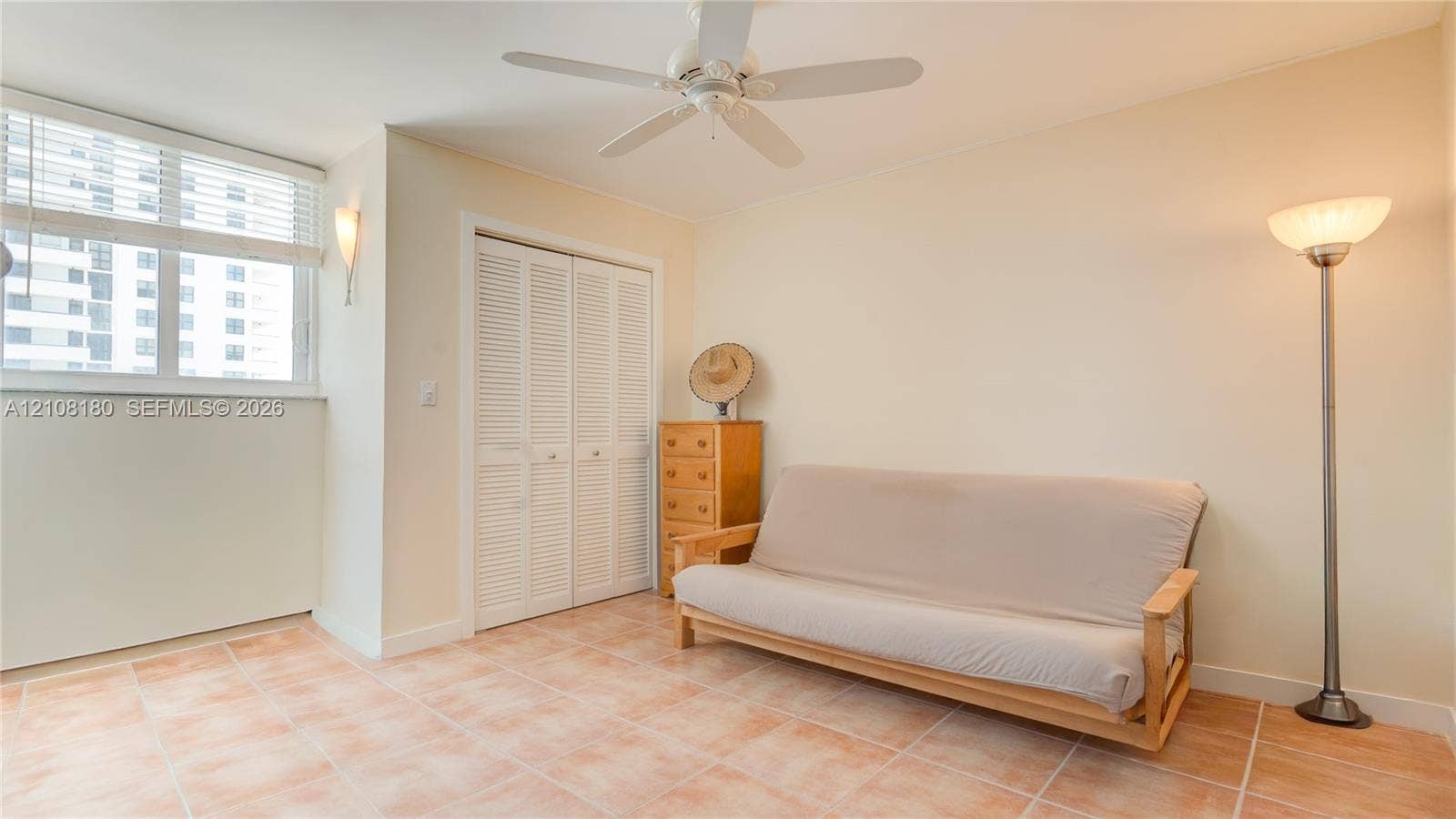 2457 Collins Avenue, #1501, Miami Beach, FL 33140 Second bedroom with ceramic tile flooring, white louvered-door closet, ceiling fan with integrated lighting, and wall-mounted sconce