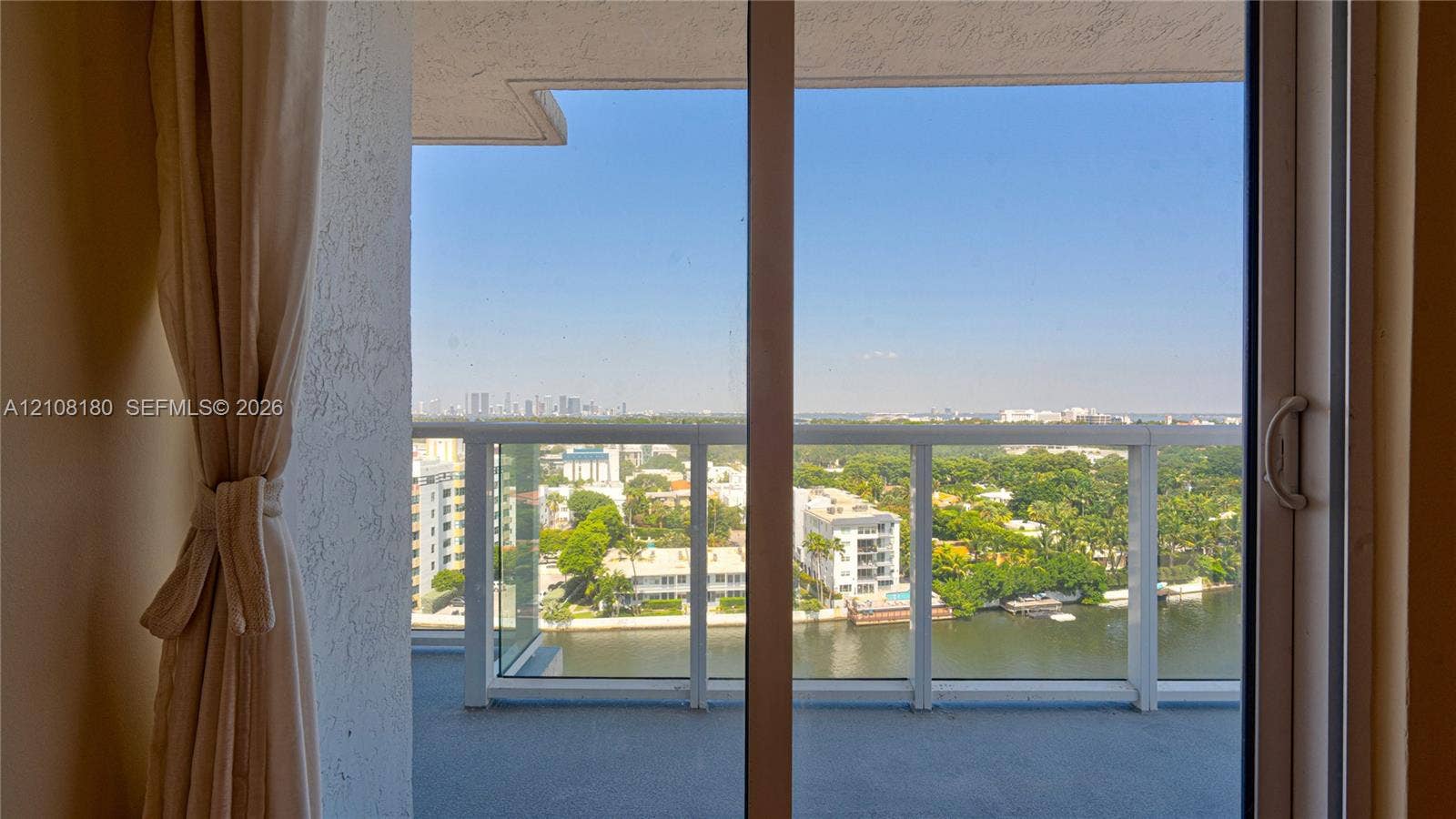 2457 Collins Avenue, #1501, Miami Beach, FL 33140 Private balcony featuring a glass-panel railing, sliding glass door entry, and water-front cityscape backdrop